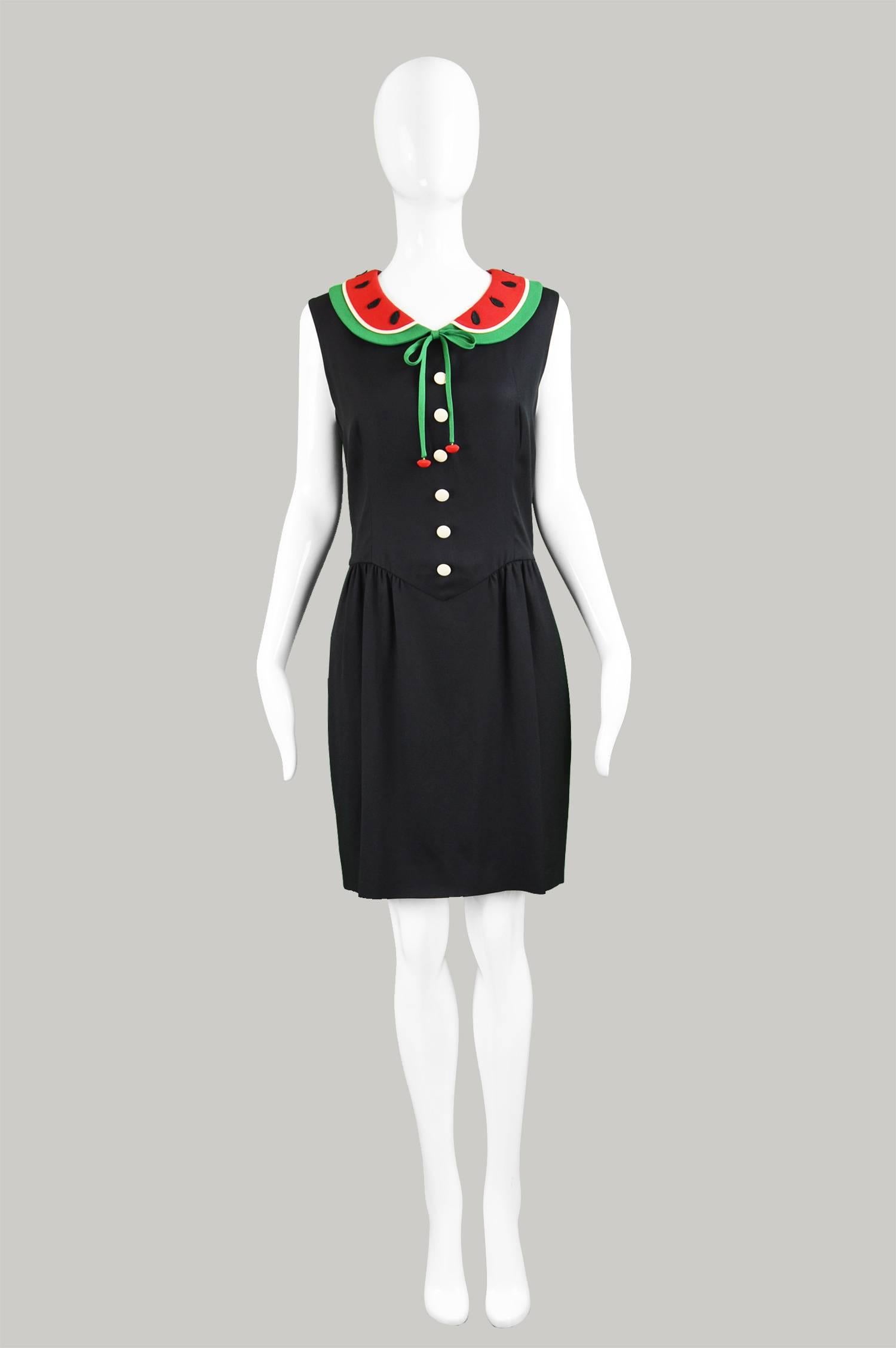 A fun and whimsical vintage Moschino dress from the 90s by genius Italian designer Moschino, for the highly collectable Cheap and Chic line. In a black crepe with off-white covered buttons and a watermelon style peter pan collar with embroidered