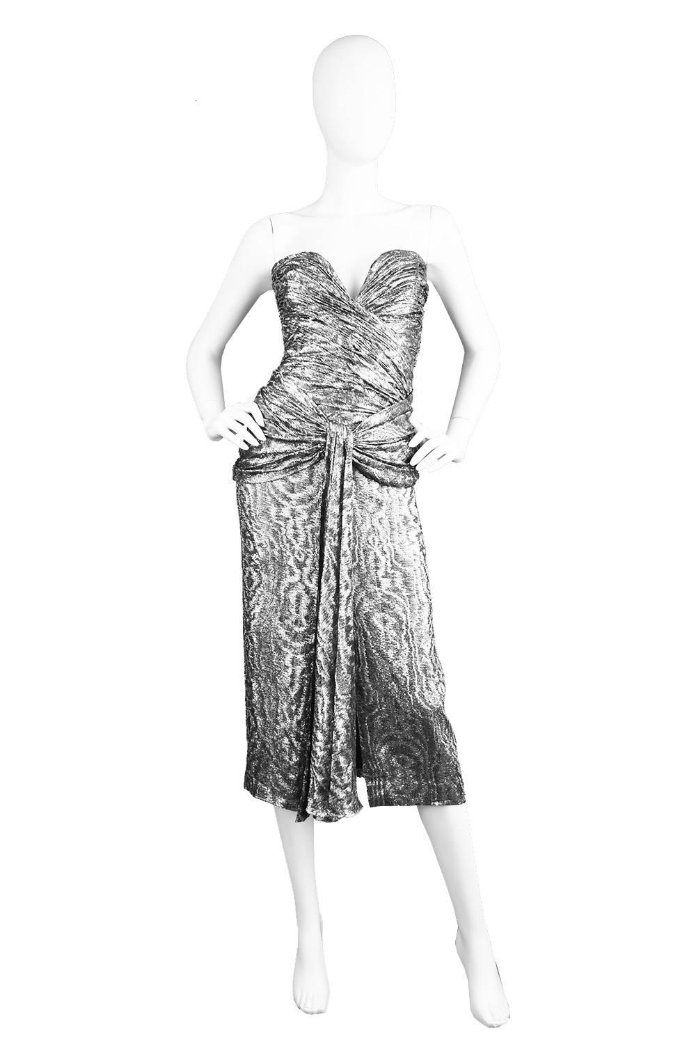 An incredibly sexy and elegant vintage Vicky Tiel dress from the 1980s in a silver lame fabric. 

Estimated Size: UK 6/ US 2/ EU 34 
Bust - 32” / 81cm
Waist - 24” / 61cm
Hips - Up to 36” / 91cm
Length (Bust to Hem) - 38” / 96cm

This stunning