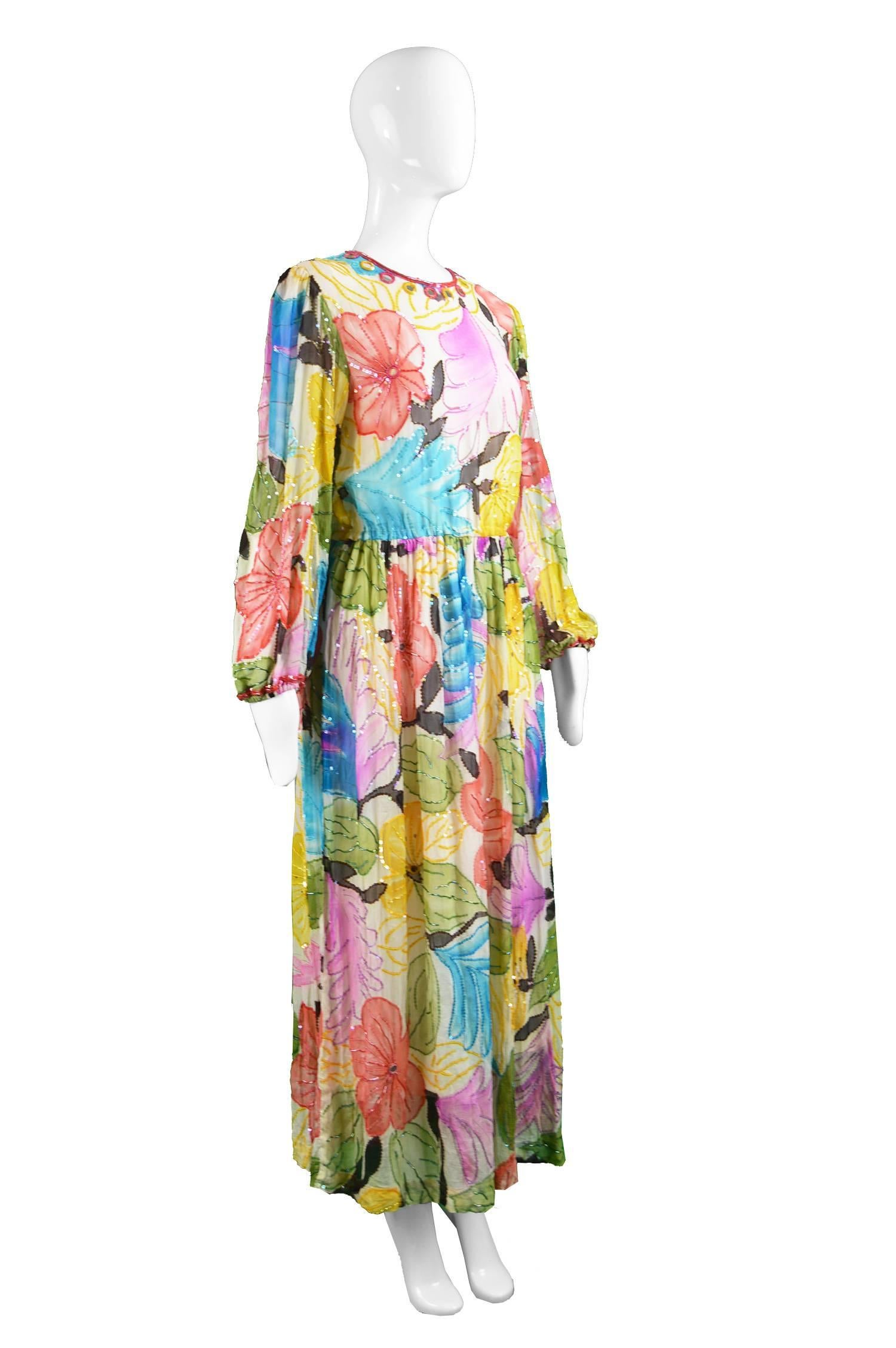A breathtaking vintage evening dress from the 70s by New York couturier and luxury designer, Swee Lo, known for her beaded silk gowns. This stunning example has a bohemian watercolour style print with mirrorwork at the top and glass beading adding a