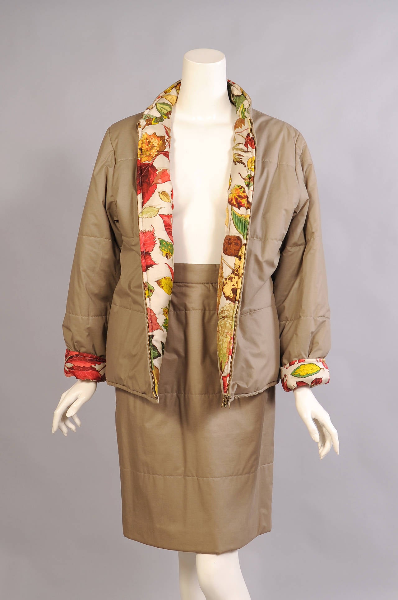 A classic Hermes scarf print of colorful leaves is used for one side of this reversible jacket. The other side is a cotton blend in a dark khaki color. The jacket zips up the front has pockets on both silk and cotton sides. A matching quilted khaki
