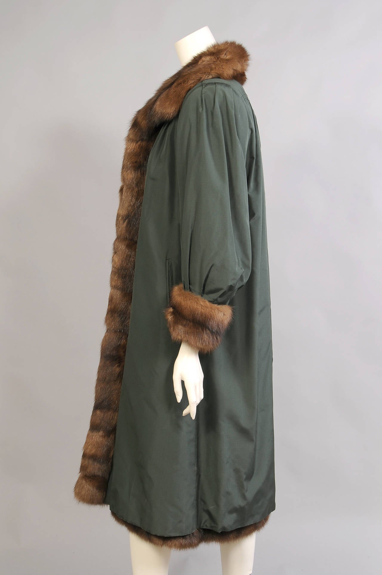 A deep green all weather coat is lined with luxurious light weight Russian sable. The coat has a lovely stand up collar and deep sable cuffs. There are fur hooks at the center front and the coat has two pockets. It is in excellent