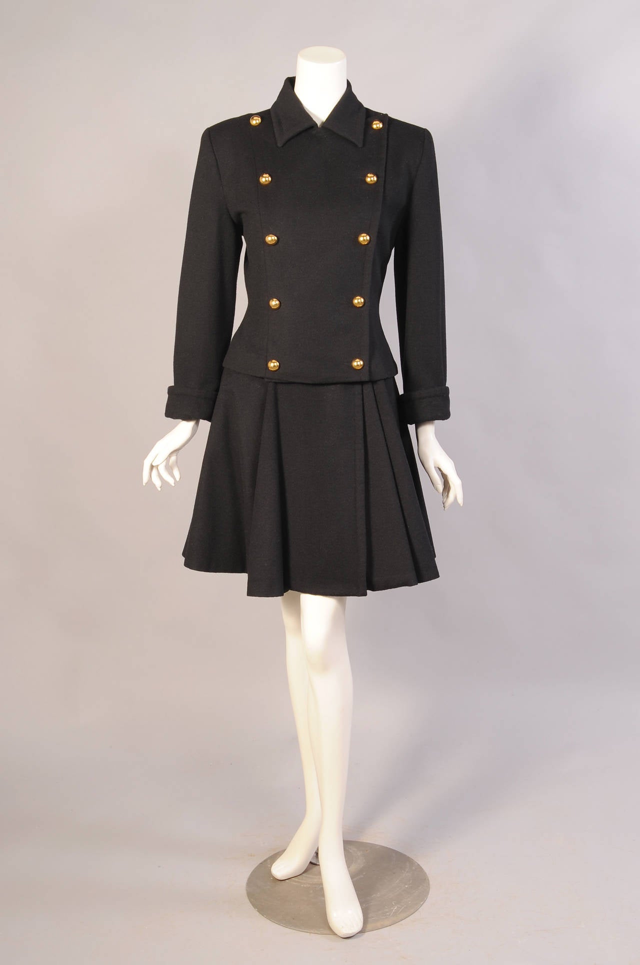 A wool and cashmere blend is used for this flirty skirt suit. The double breasted jacket has ten round brass buttons and the matching skirt has four more. Both pieces are fully lined, have extra buttons sewn inside, and they are in excellent