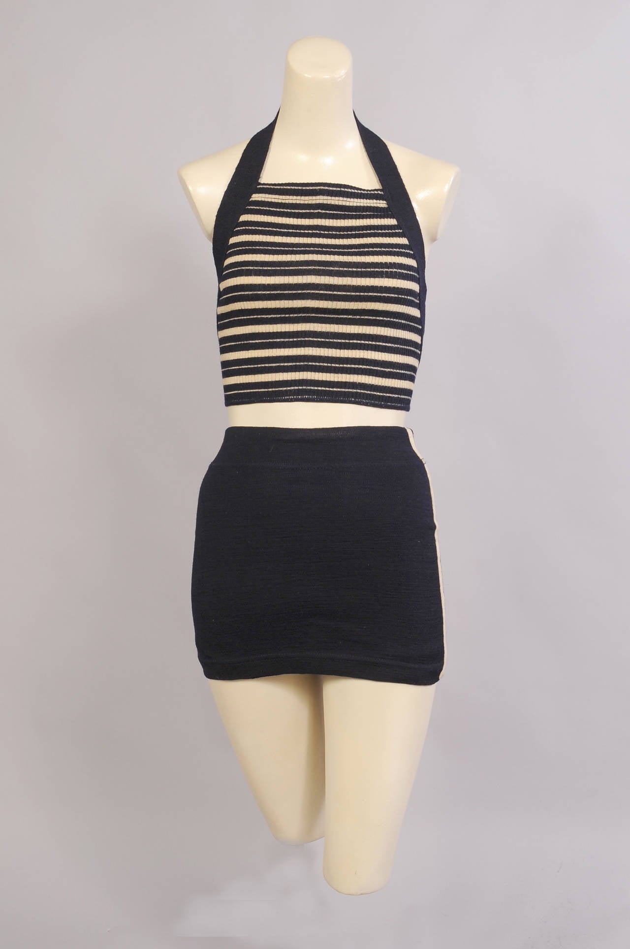 A fabulous survivor from the Roaring 20's this navy blue and cream bathing suit is in excellent condition. The bare midriff top has a striped front bordered in solid navy. It ties in back at the halter neckline and the waist. The bottoms have a
