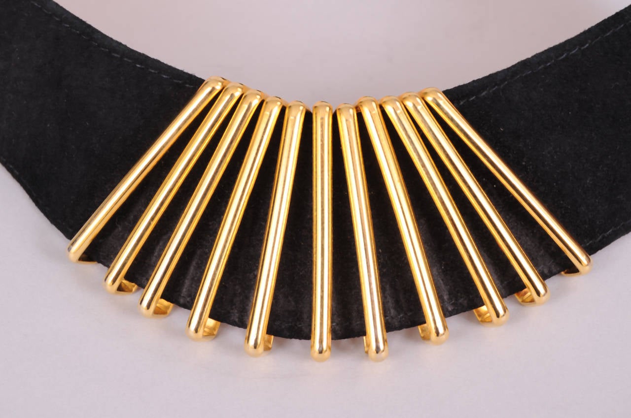 A stylized fan made from gold toned metal bars is the focal point of this black suede belt. It buckles in the back and is marked a size 70. It fits a size 27