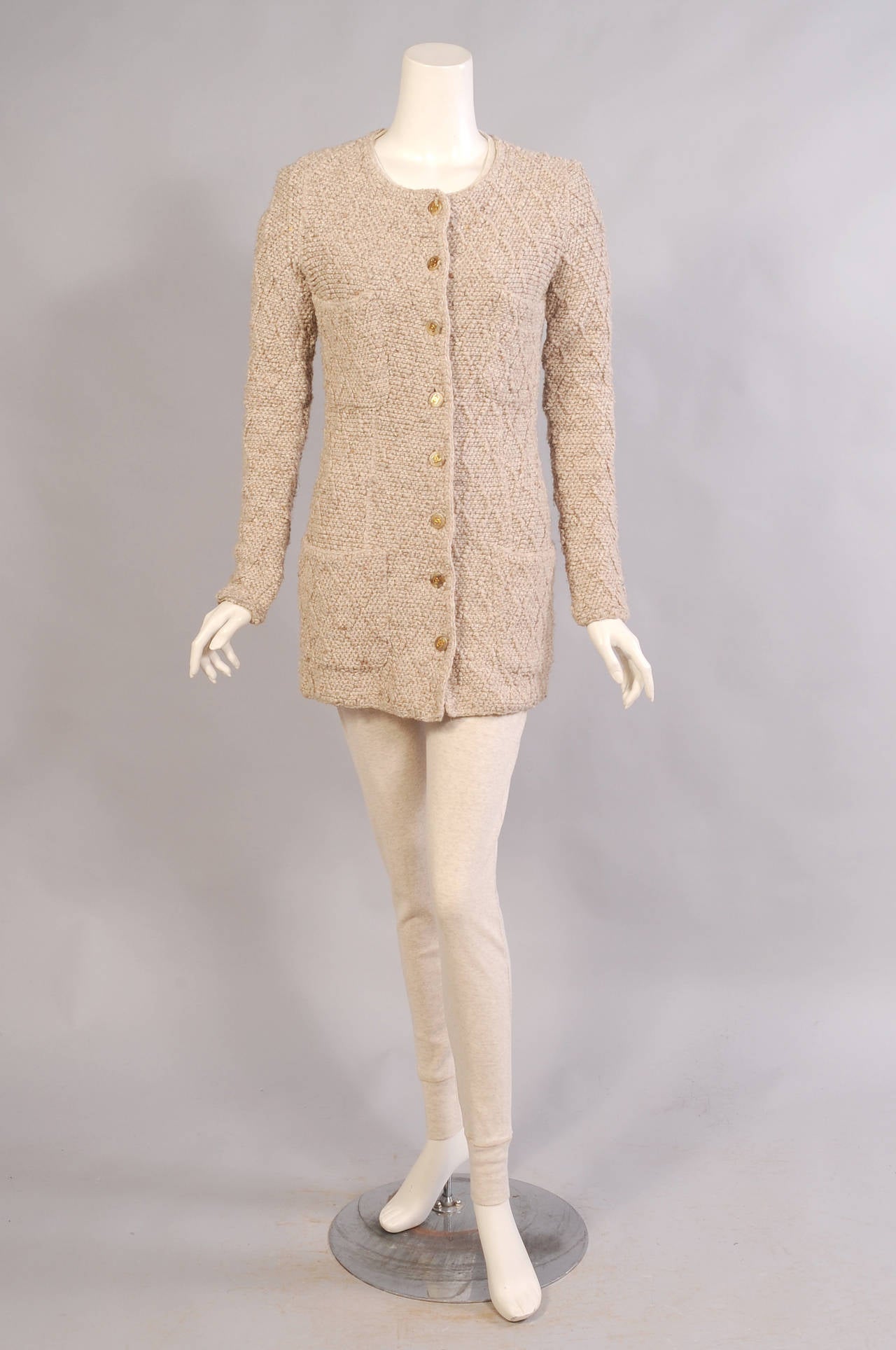 A classic beige tweed knit jacket has a lattice pattern for added interest. The Chanel  double C logo buttons and four patch pockets add to the look. It is in excellent condition and marked a size 38.