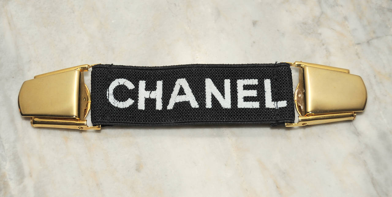 Clip this great piece on a jacket, vest, coat or sweater for a snug fit and a slimmer look. The gold toned metal clips are marked 23 for the Chanel collection. The black elastic Is stenciled Chanel.