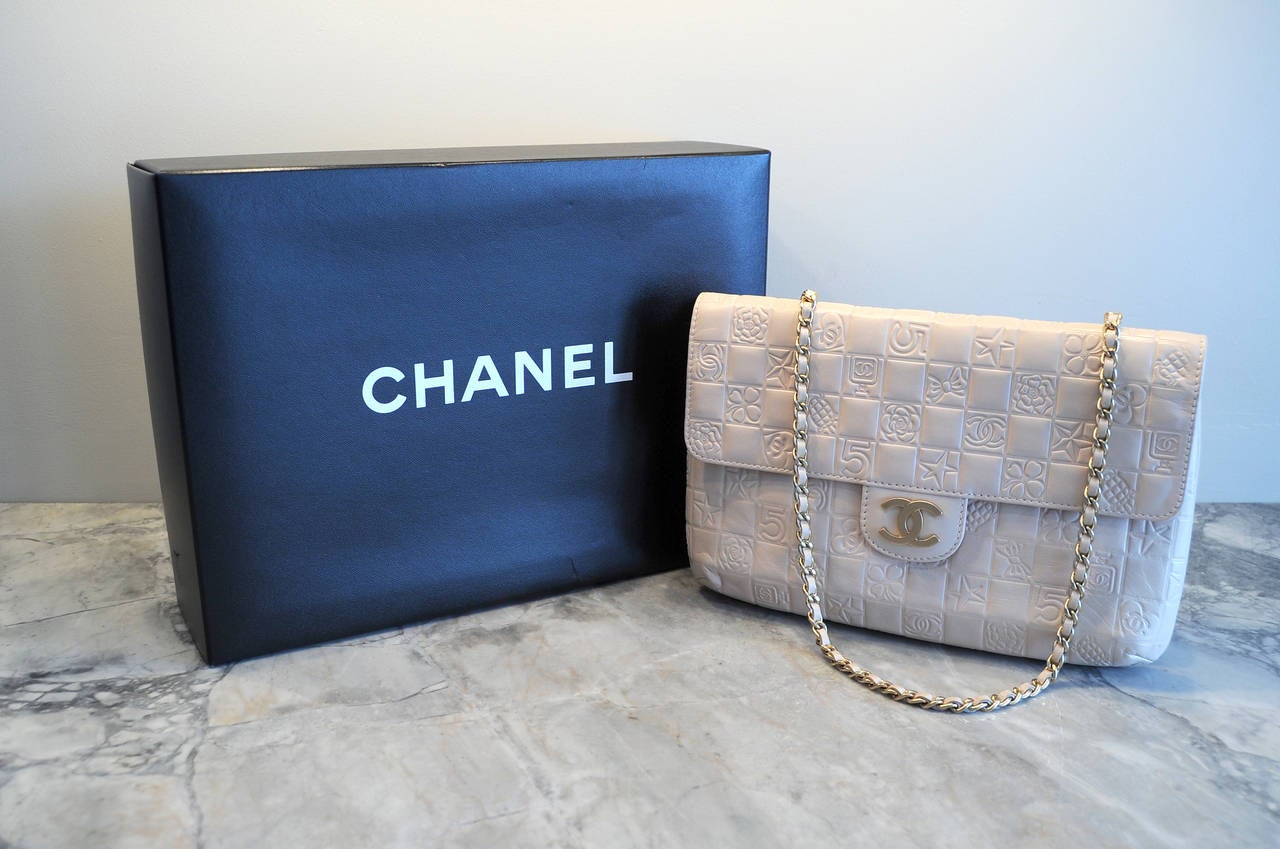 From a Park Avenue estate this pristine double sided Chanel bag is impressed with all of the iconic Chanel logos. The Number 5, a perfume bottle, a camellia and a heart with double C's are among the designs on this blush colored leather  bag. The