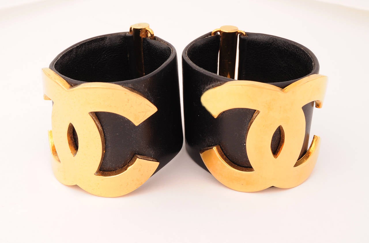 The classic Chanel double C logo is front and center on these wide black leather cuffs. They slip on and have a gold toned metal cylinder at the back. They are in excellent condition.
Measurements;
Height 2 .25