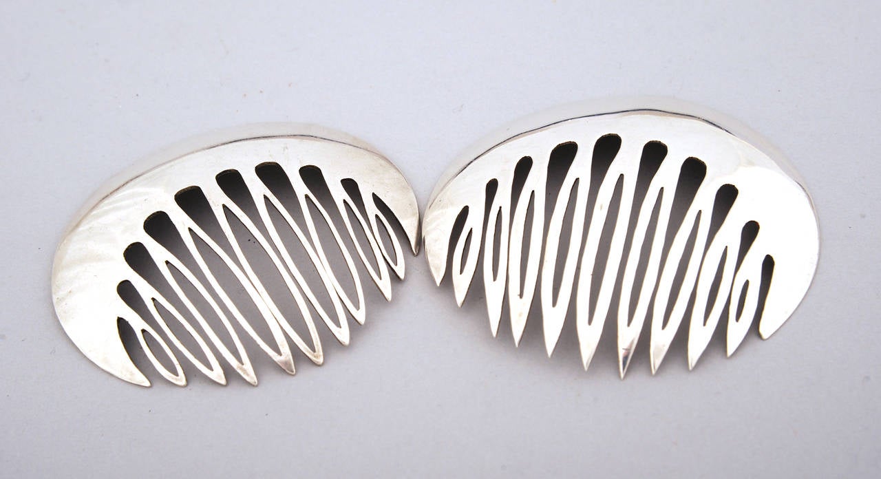 This pair of Tane hair combs are designed in a striking 1970's form.. The combs are one circular piece with a wide band of silver at the top and the comb cut out below. They are both stamped on the back and they are in excellent