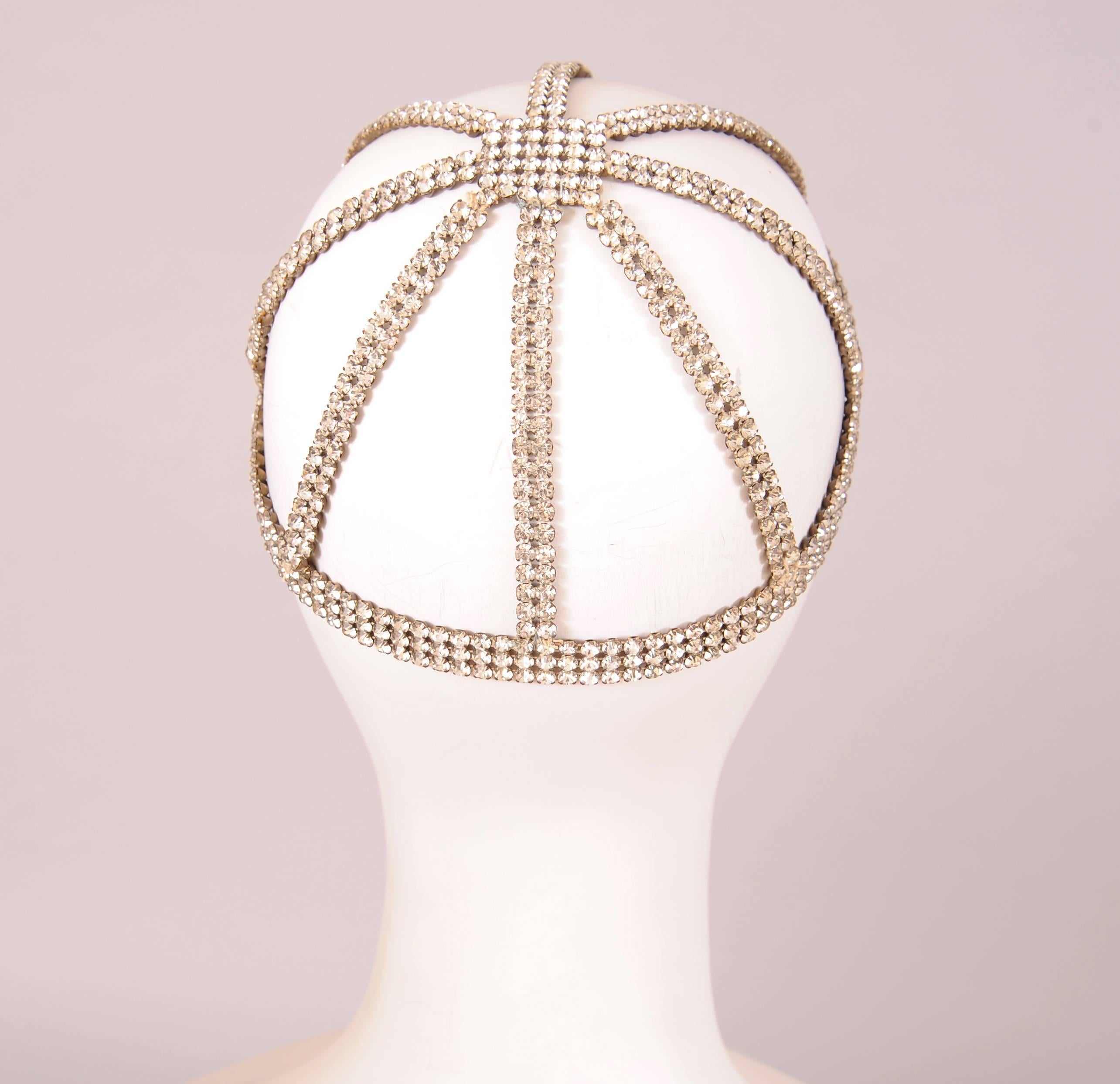 A square of sparkling rhinestones sits at the center of this stunning evening head piece. Eight double rows of rhinestones run vertically to the brow band at the base. This rare survivor from the Flapper era is entirely hand made from rhinestones.