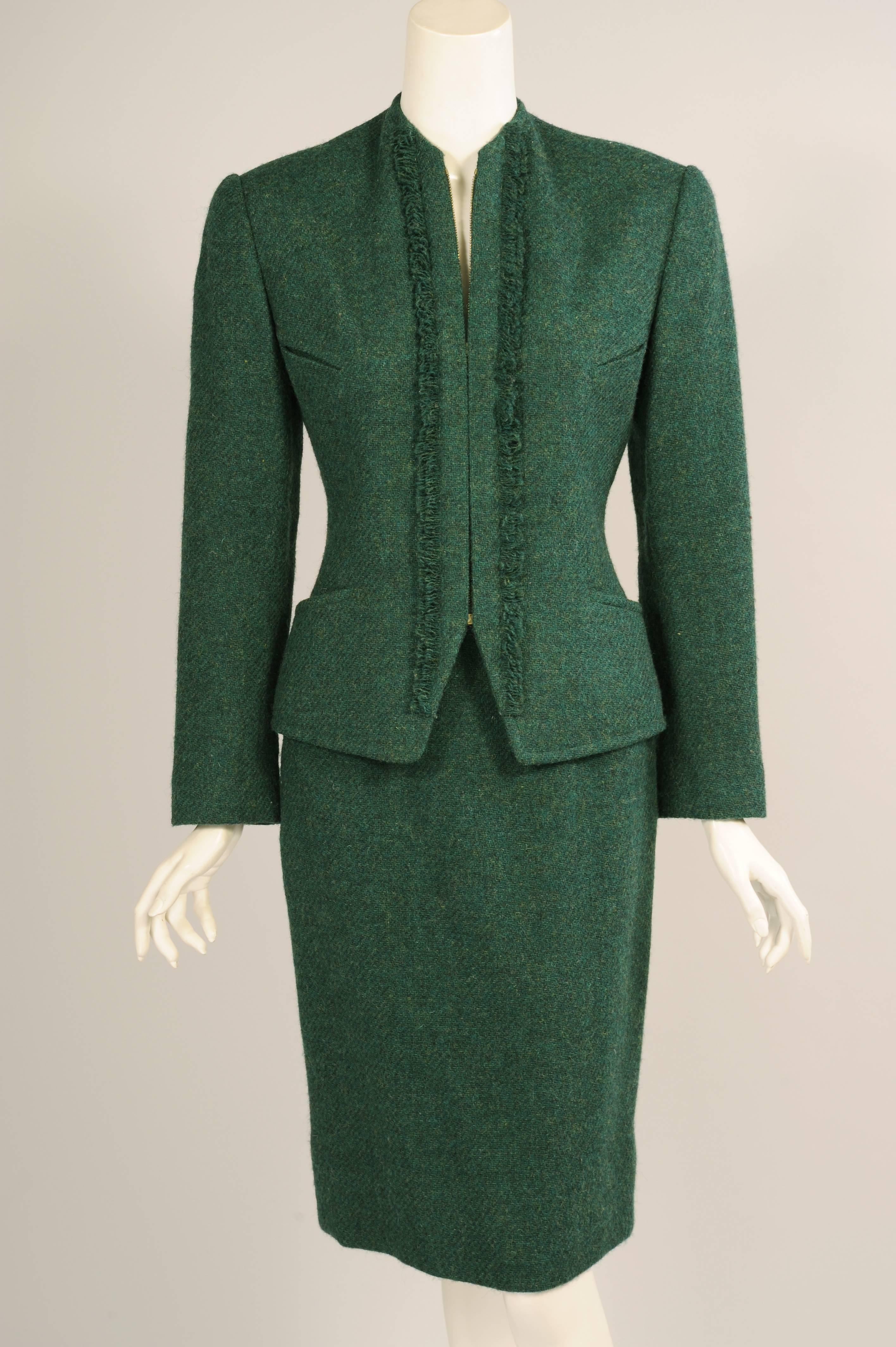 A fine heather green wool, accented with a vertical fringe on either side of the center front zipper is used for this chic jacket and skirt from Hermes, Paris. The fitted collarless jacket has four pockets. It is fully lined and marked a size 40.