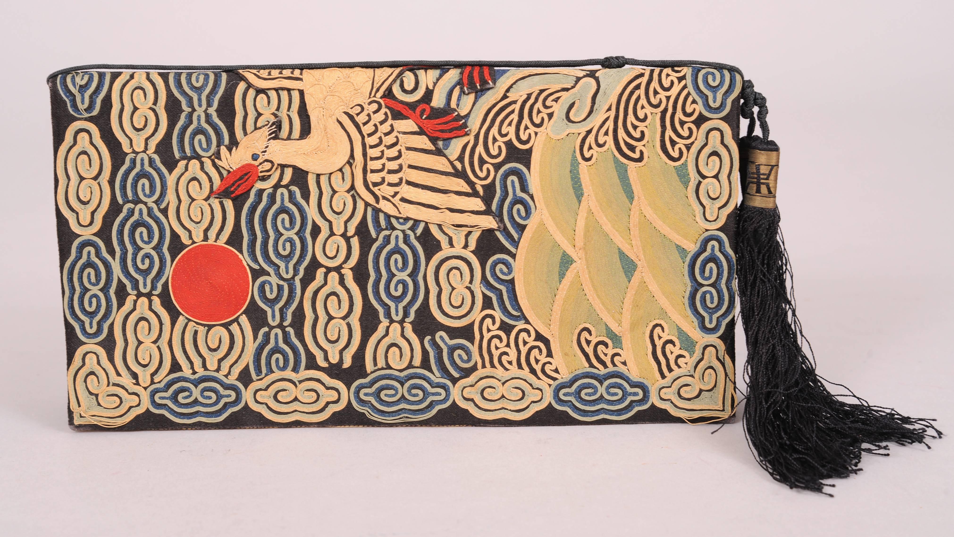 Colorful silk and metallic thread embroidery in a cloud pattern serves as the background for the beautiful appliqued bird at the center of this 1930's clutch.The bag has a black silk cord and tassels and it is lined in a tone on tone Chinese silk.