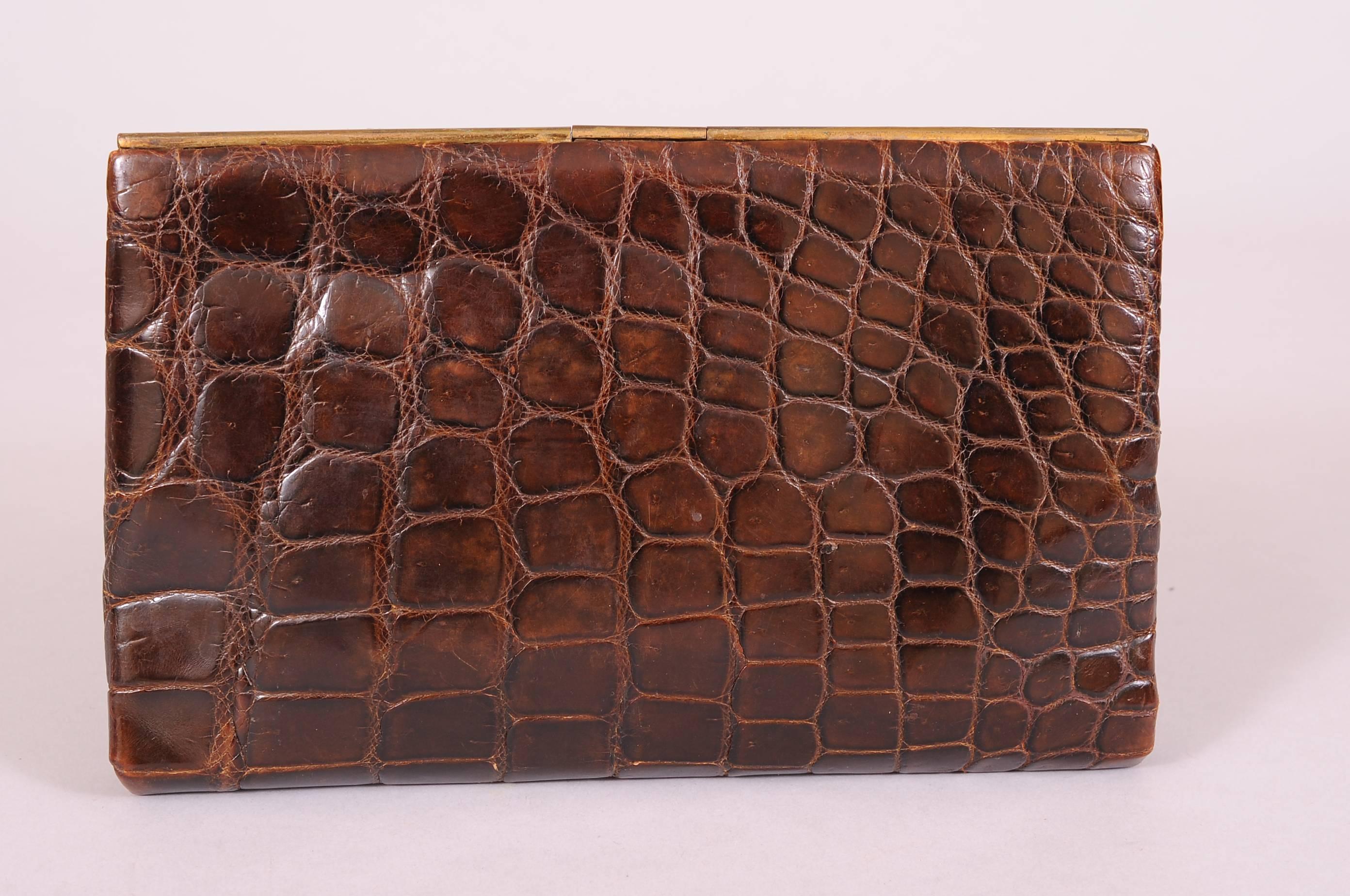 Retailed by Vickery, Regent St. London this 1930's crocodile clutch is spare and elegant. The brass frame barely rises above the crocodile skin. The small handle on the back is placed on the left side, adding an interesting design element. The bag