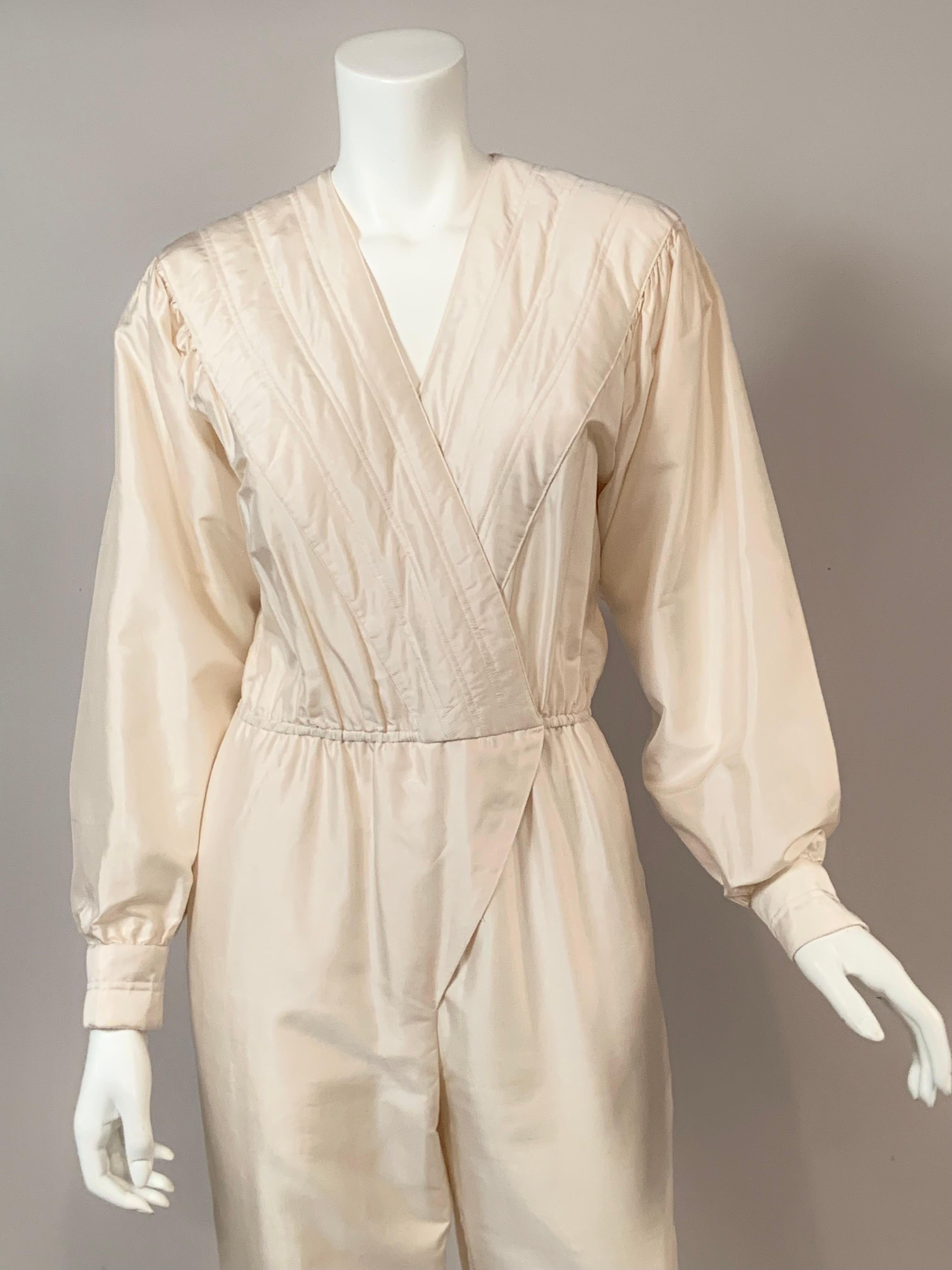 Cette élégante combinaison en soie thaïlandaise blanche présente un corsage enveloppant matelassé, des manches dolman avec matelassage sur les poignets et une fermeture à crochet à la taille qui dissimule une fermeture à glissière sur le devant.  Le