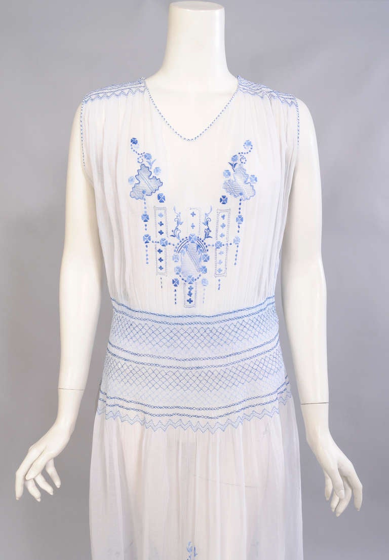 Sheer white cotton voile is hand sewn and hand embroidered creating a timeless day dress. The charming embroidery is worked in shades of blue. The shoulders and hips are hand smocked and the bodice and skirt have hand embroidery and drawn work. 