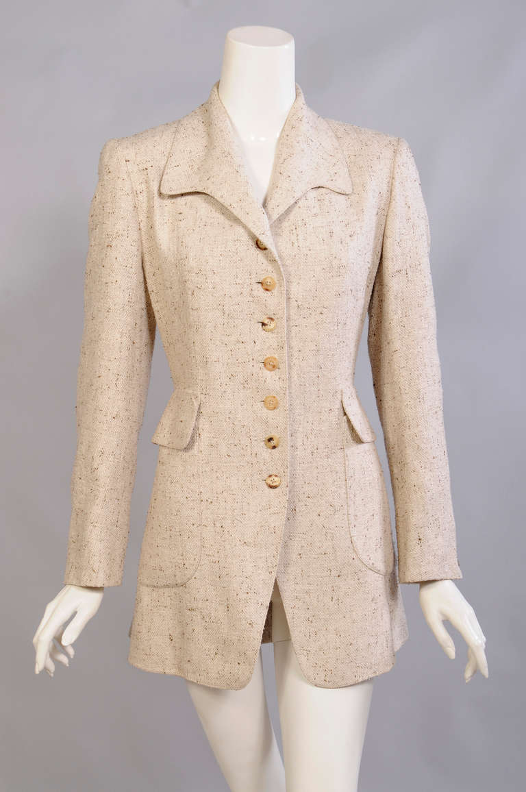 A natural tweedy raw silk is accented with Hermes horn buttons and tailored in the equestrian style. There are two large patch pockets and a stylish peplum at the back. The jacket is fully lined in Hermes logo fabric and it is in excellent