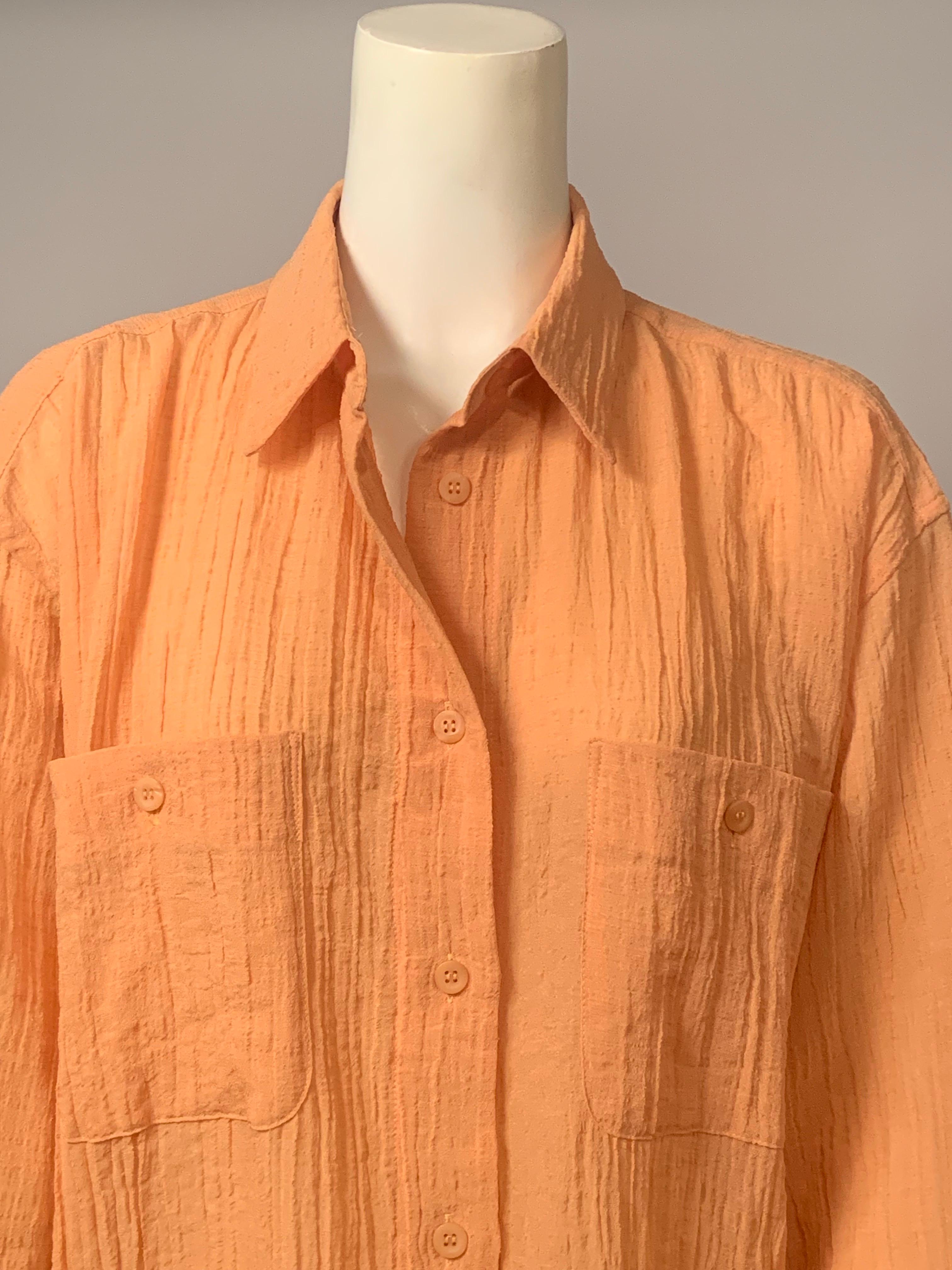 Issey Miyake utilizó un alegre tejido de color melón cuando diseñó esta exquisita camisa. Tiene cuello de pico, dos bolsillos en el pecho, mangas largas con puños y dobladillo recto con aberturas en las costuras laterales. La espalda de la camisa