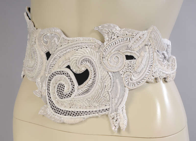 A striking and original design for a belt, this beaded belt swirls and dips in a unique pattern. All white beads, pearls, bugle beads, sequins and caviar beads embellish a black fabric belt. It snaps closed and bears the Christian Dior Boutique