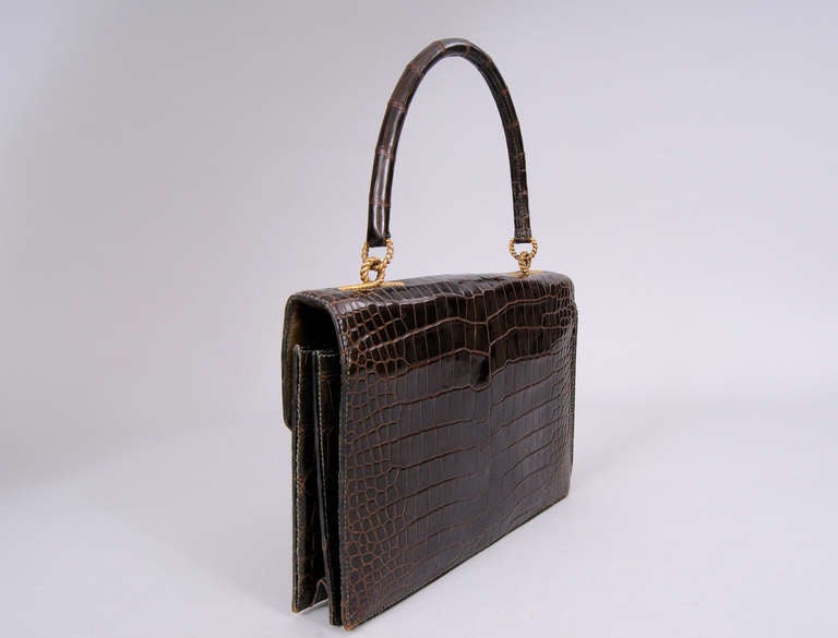 Rich brown crocodile skin is accented with gold rope twist hardware on the clasp and handle of this vintage crocodile bag from Hermes, Paris. The bag is lined in the softest olive green lambskin. It has a large slip pocket and two interior sections.