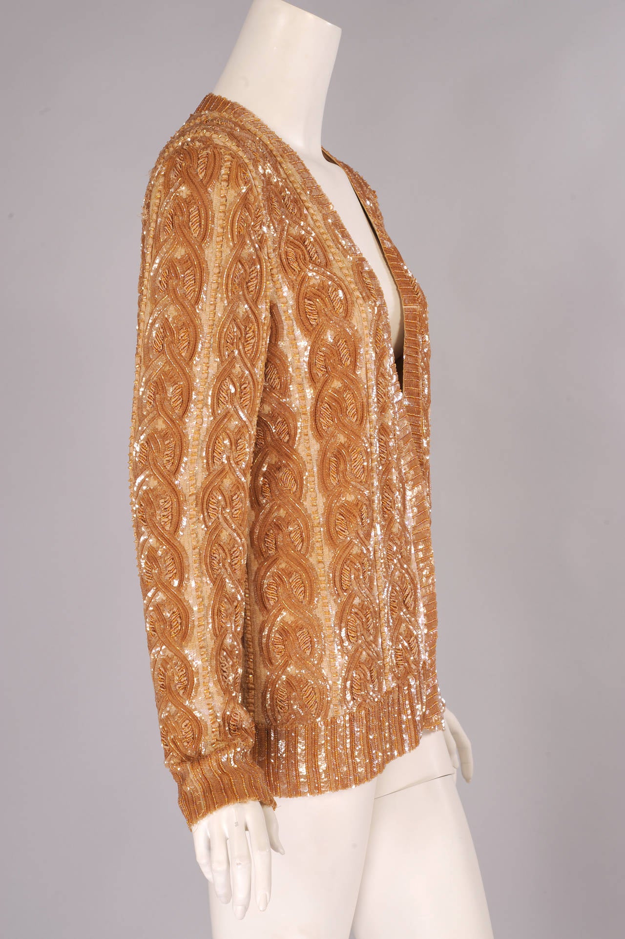 Diese elegante Jacke, die von einem klassischen Zopfstrickpullover inspiriert ist, ist ein erstaunliches Beispiel für Perlenstickerei und Handstickerei. Die Borten sind mit Pailletten und Kaviarperlen verziert. Für den Zopfstich mit Seidenstickerei