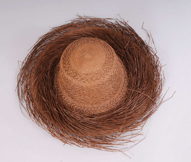 The detail in this cocoa colored straw hat is amazing. The tightly woven straw has a larger straw pattern woven through it. Straw fringe goes in one direction on  the brim and the other direction on the edge of the hat. Never worn, it is in