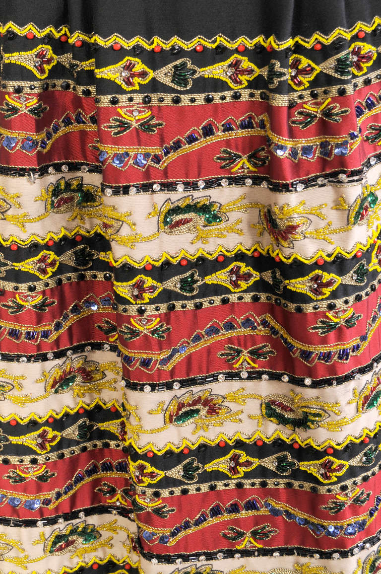 A stunning example of beadwork and embroidery this colorful evening skirt was made in Mexico in the 1950's. Horizontal bands of red, cream and black are lavishly embellished with gold metallic embroidery and multi color beadwork. The small scale and