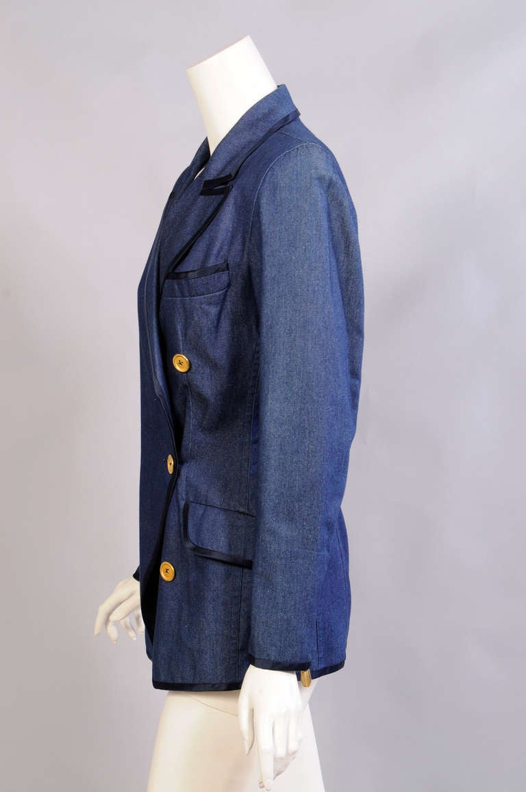 Donna Karan used a blend of silk and cotton to create a more elegant denim. This double breasted jacket is piped with navy blue satin and accented with gold toned buttons and zippers with gold toned pulls on the sleeves. It is marked a size 6 and it