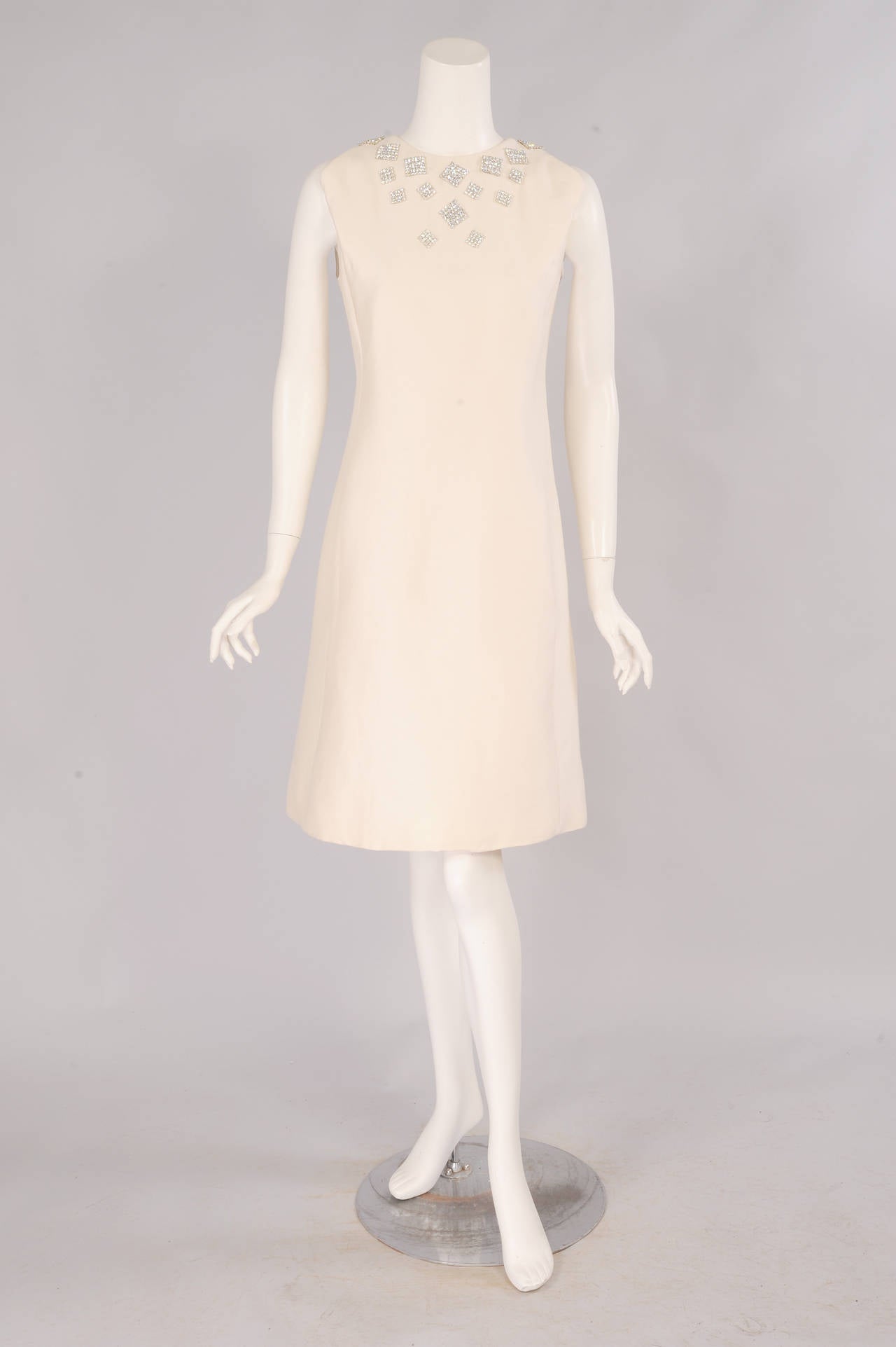 A chic silk dress, with an interesting shoulder detail, is embellished with squares of prong set rhinestones for a modern take on a diamond necklace. The dress has two pockets concealed in the seams, a center back zipper, and it is fully lined. It