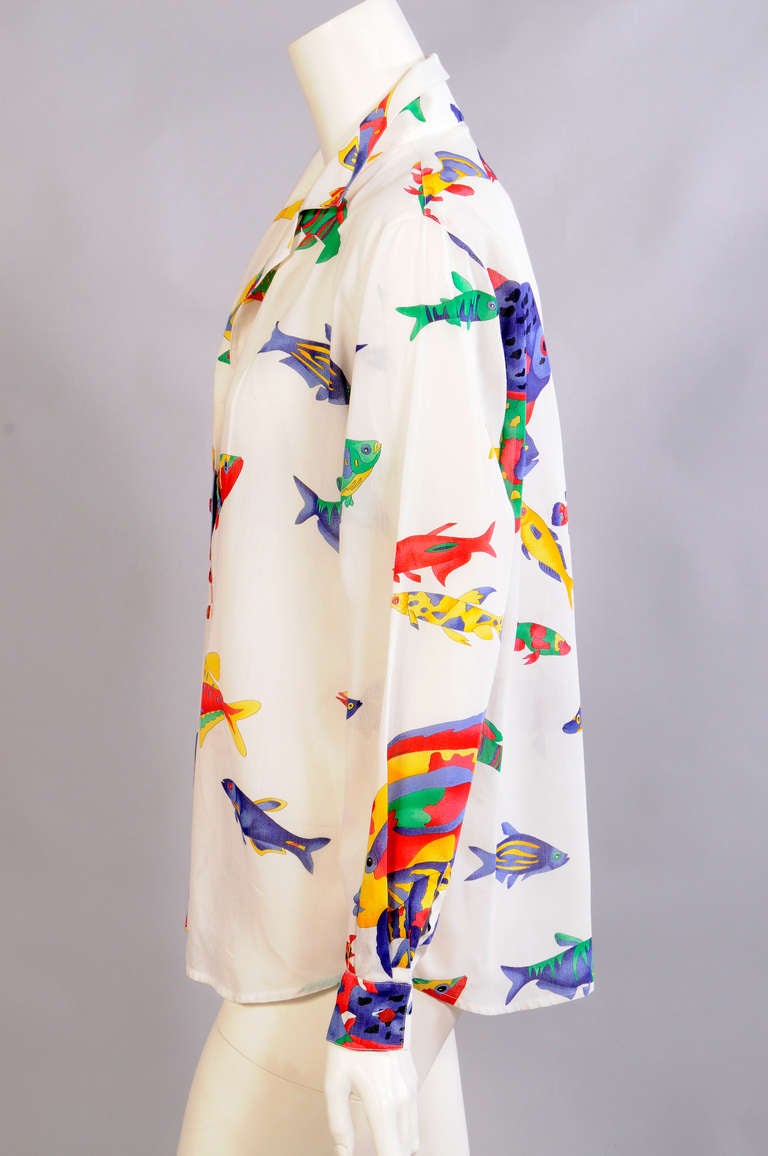 Tropical fish in bright primary colors swim across this cotton voile shirt from Leonard, Paris. It is in excellent condition.
Measurements;
Shoulders 17