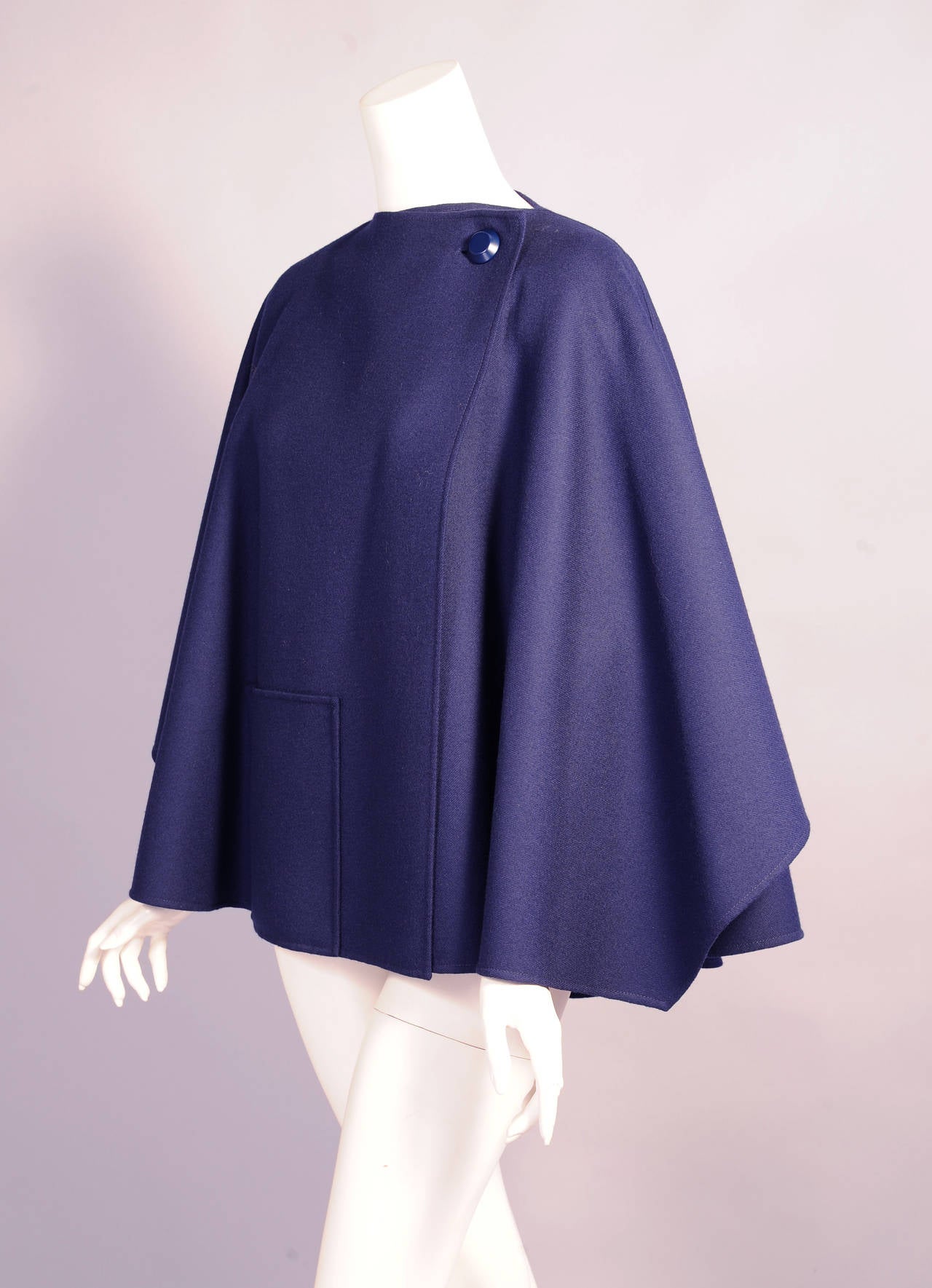 This striking short cape is spare and voluminous at the same time. The design is classic Madame Gres and the single button closure and off center single patch pocket are clean and elegant. The unlined cape is in excellent condition. One size fits