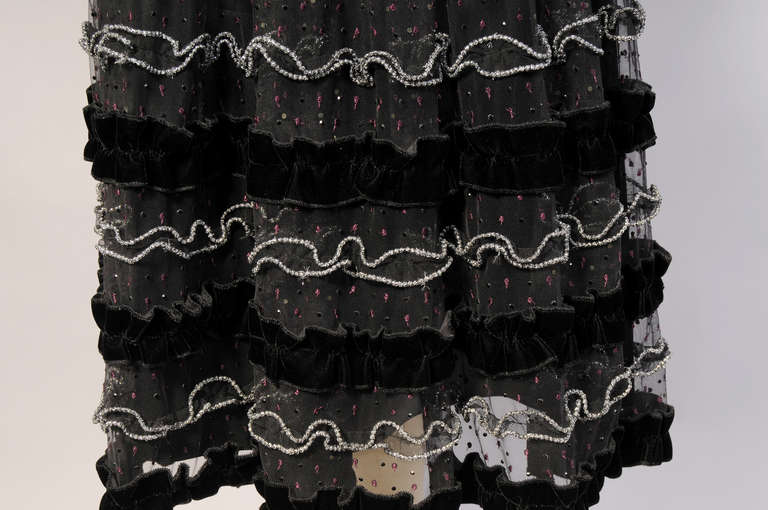 Black tulle is embellished with silver bead edged ruffles,  black velvet ribbons, black beadwork and burgundy embroidery. It is lined with black satin and has a left side zipper. This flirty skirt is in excellent condition.