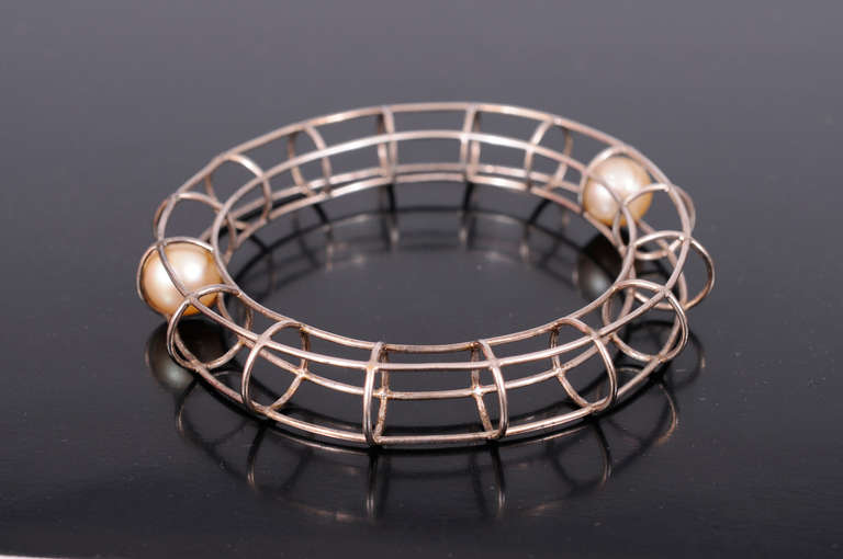 A sterling cage encloses two pearls, but leaves just enough room for to roll inside, creating a very witty bracelet. It is in excellent condition and it will fit a large size.
Measurements;
Interior circumference 8 1/2