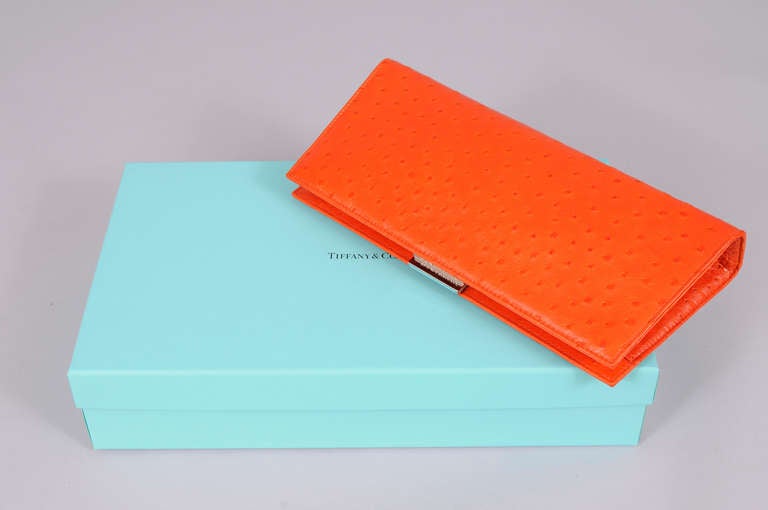 Tangerine ostrich skin makes this eye an catching bag and the Tiffany blue leather lining makes it a little jewel. Never used, the pristine bag comes with care cards inside, the original sleeper bag and the Tiffany box. The bag has one zippered