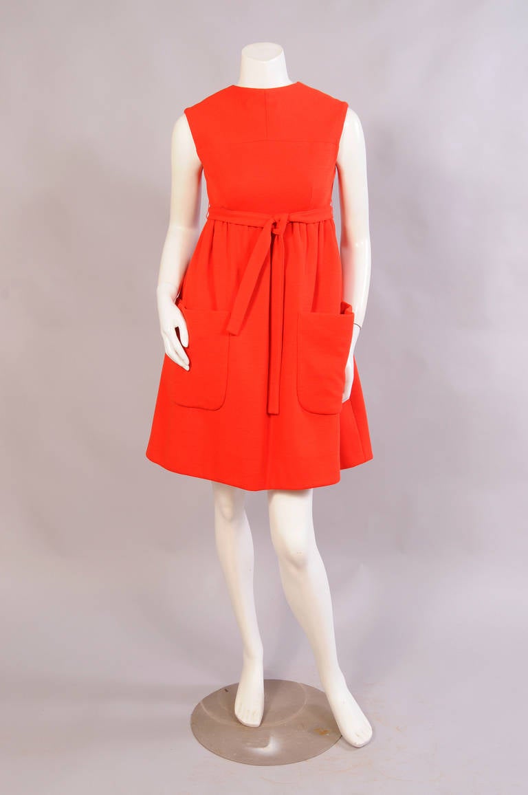 An Empire waistline and two large patch pockets define the front of this wrap dress. The back has a low V neckline and interior hooks and snaps. The dress is fully lined and in excellent condition.