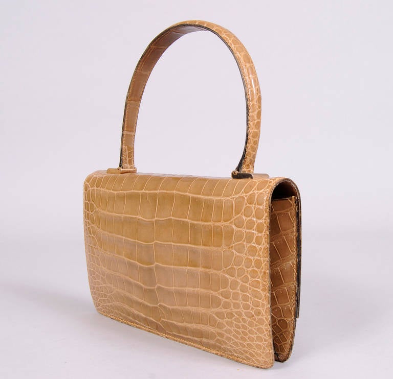 Classic French design and beautiful taupe alligator skin make this 1960's bag a timeless piece. It has a rigid handle and a push button closure. The interior is lined in a matching leather with a zippered pocket and a slip pocket. The bag is in