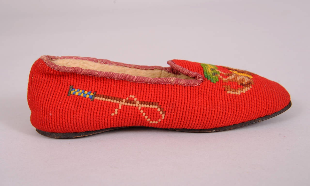 Bright red hand made needlepoint slippers are lined in sheepskin to keep those little toes warm. They each have a frolicking pony on the front and a riding crop on both sides. The leather soles show very minimal wear. The slippers are Victorian and