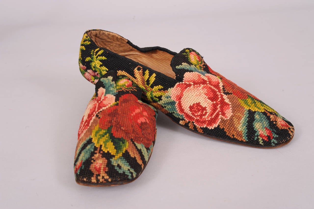Hand made in Philadelphia these Victorian needlepoint slippers have a beautiful and colorful floral design set against a black needlepoint background. The slippers are lined in soft tan kidskin and one bears the paper label from James West,