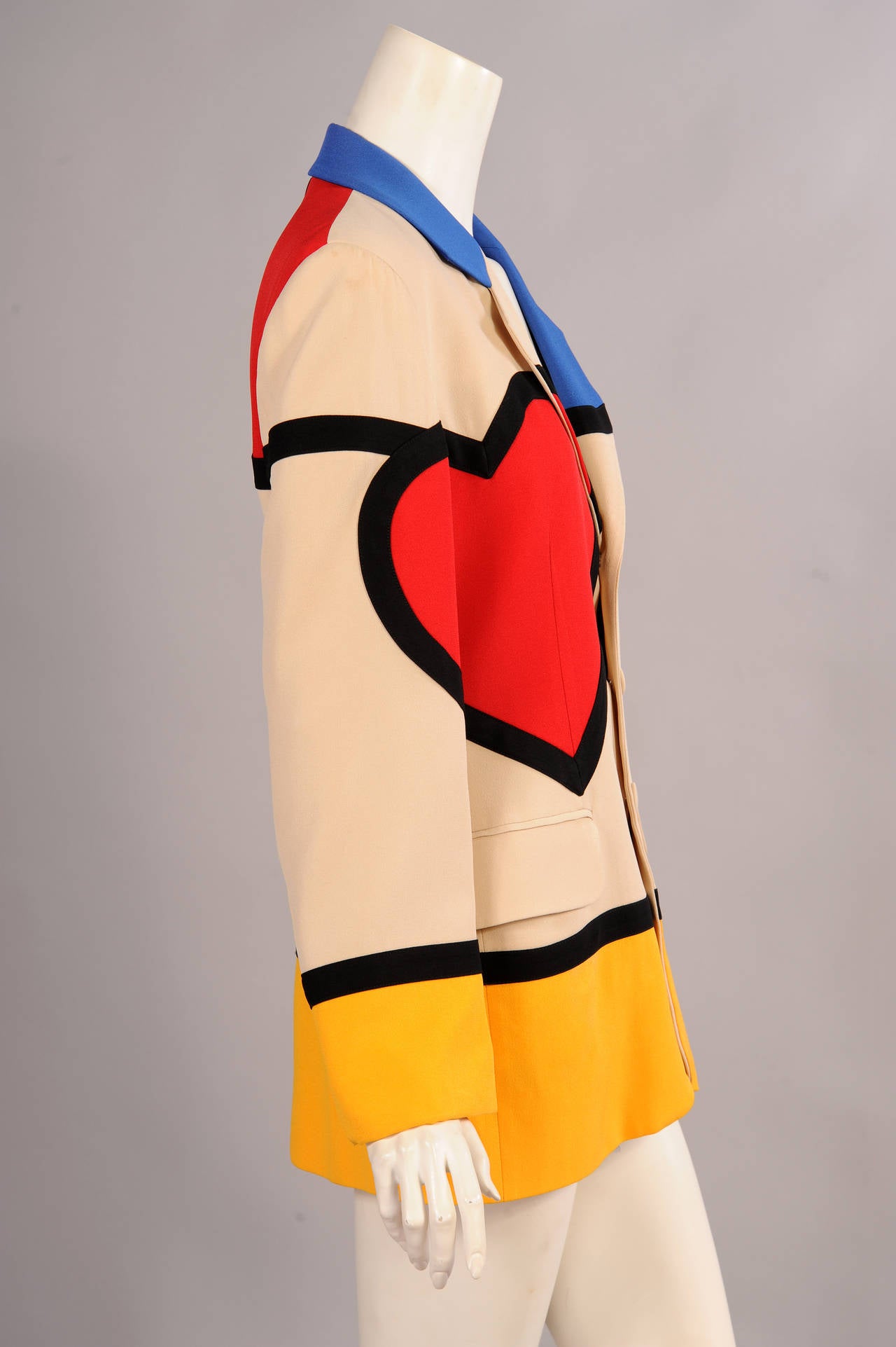 A Mondrian inspired multi colored design serves as the background for the large red heart on the right side of this jacket. On the back, the left shoulder is embroidered with the phrase 