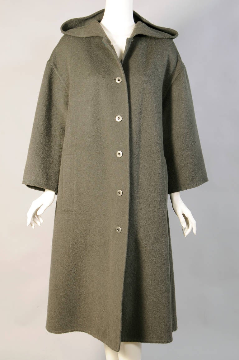 A fabulous overcoat, it is unlined and roomy enough to slip over a jacket.  There is a hood with stitching detail, metal buttons and two deep pockets. There is a generous inverted pleat at the center back. This great coat is in excellent
