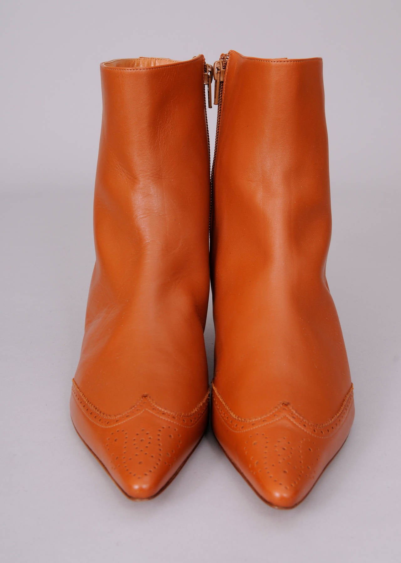 Soft caramel colored leather has a pierced decoration on the  toe cap as well as on the heel, running up the center back. The boots have a low heel, they are marked a size 40.5 and they have never been worn. They are in excellent condition.