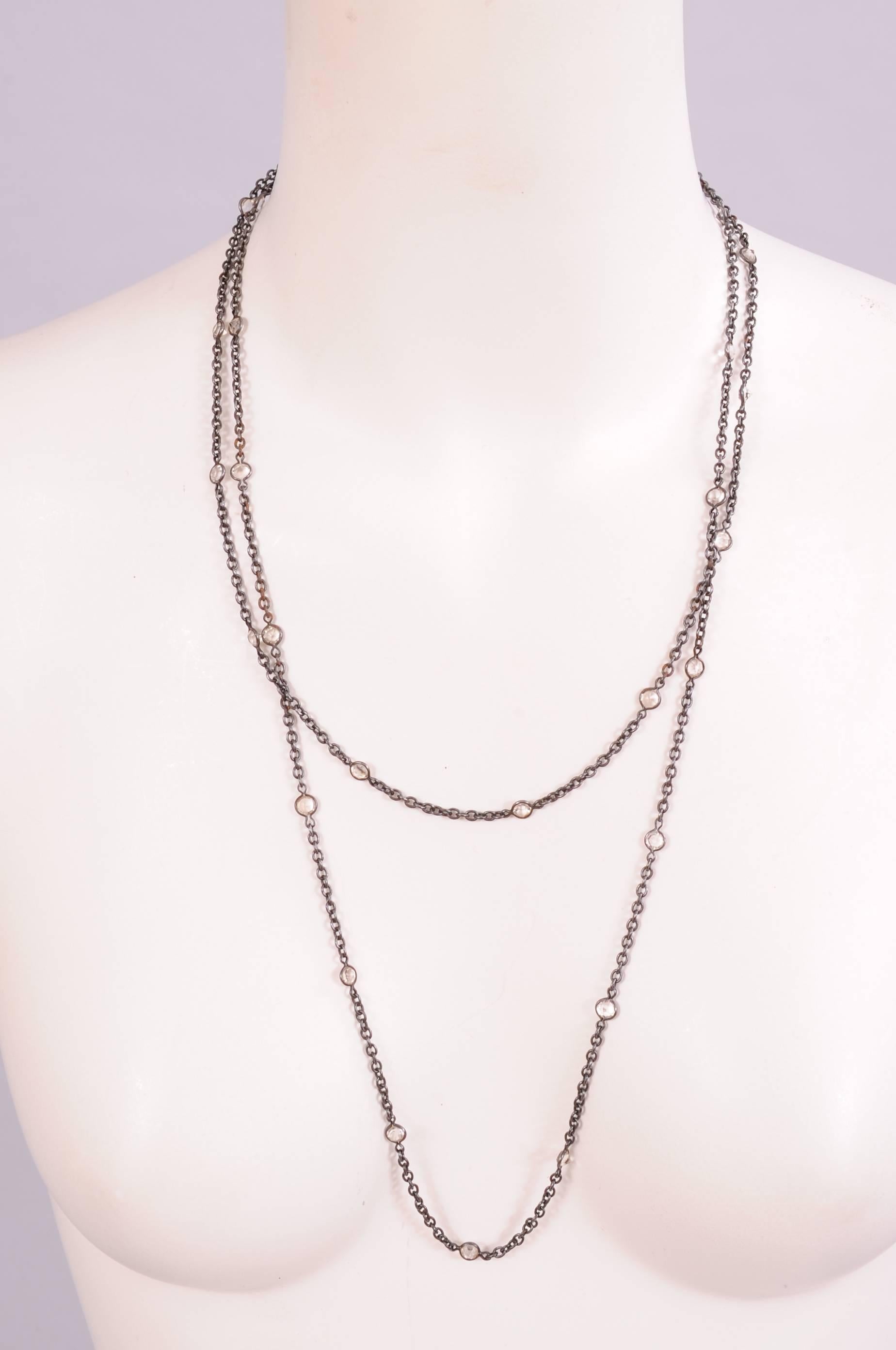A long and elegant gunmetal chain is embellished with facted faux diamonds every 1 1/2