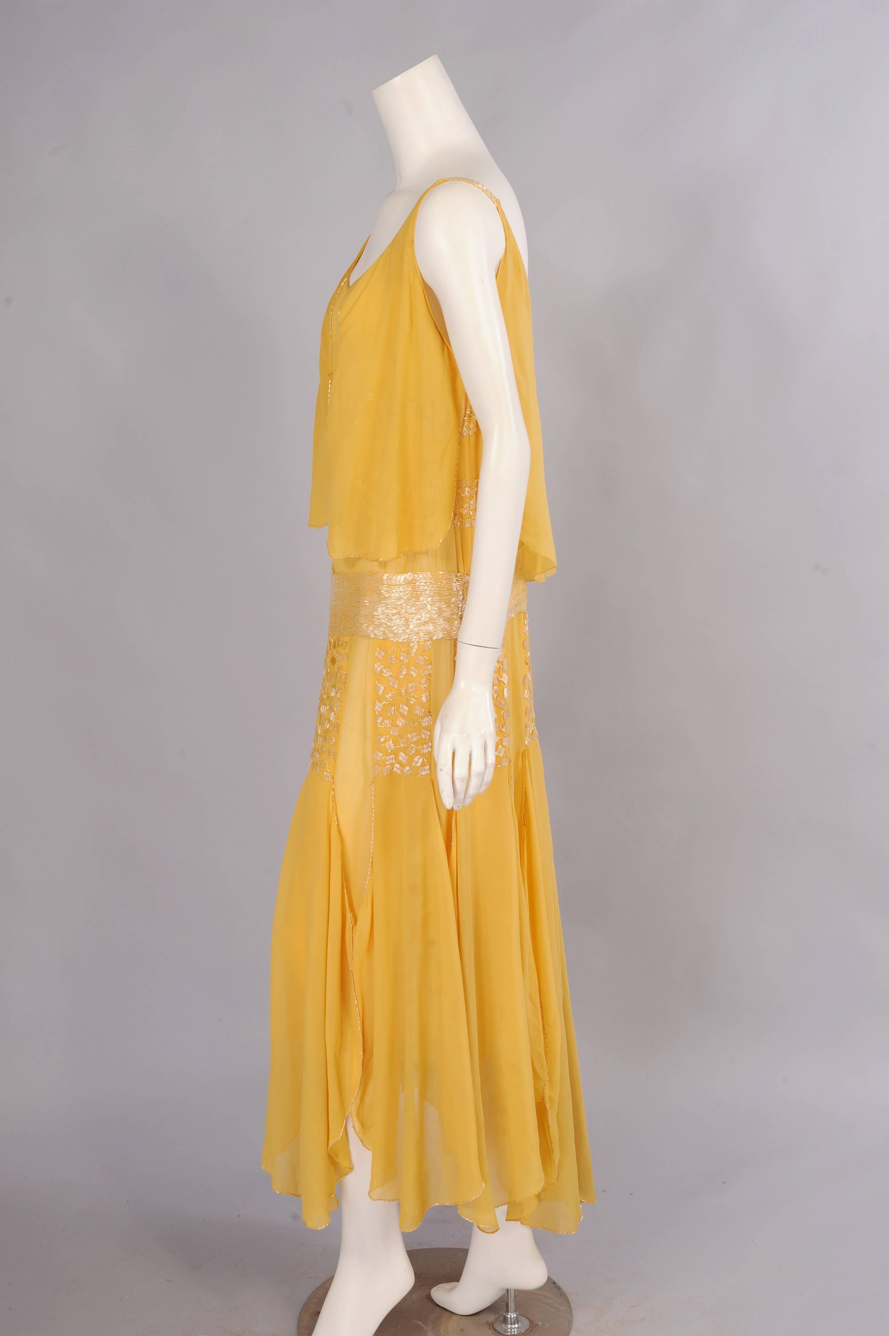 Pale yellow silk chiffon is beaded and draped to create this beautiful dress from the House of Drecoll-Beer in 1929.  The bodice is beaded with rows of bugle beaded squares set on the diagonal. A bead edged chiffon 