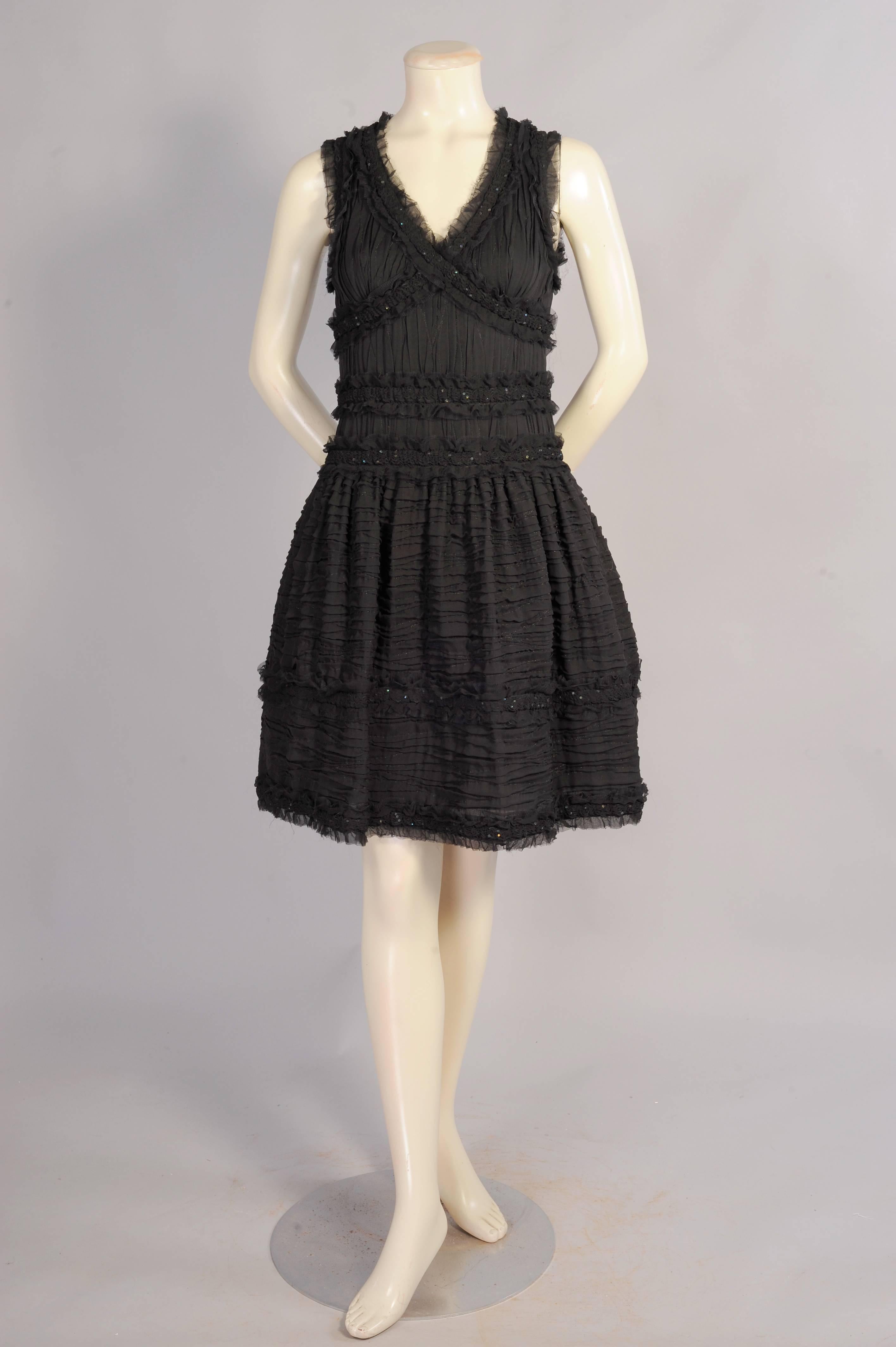 A fine black tulle is used to give this charming pleated silk and tulle dress a great shape. The sleeveless dress has bands of tulle and silk that criss cross the bodice, edge the neckline, armholes, waist and the bottom of the skirt. These bands