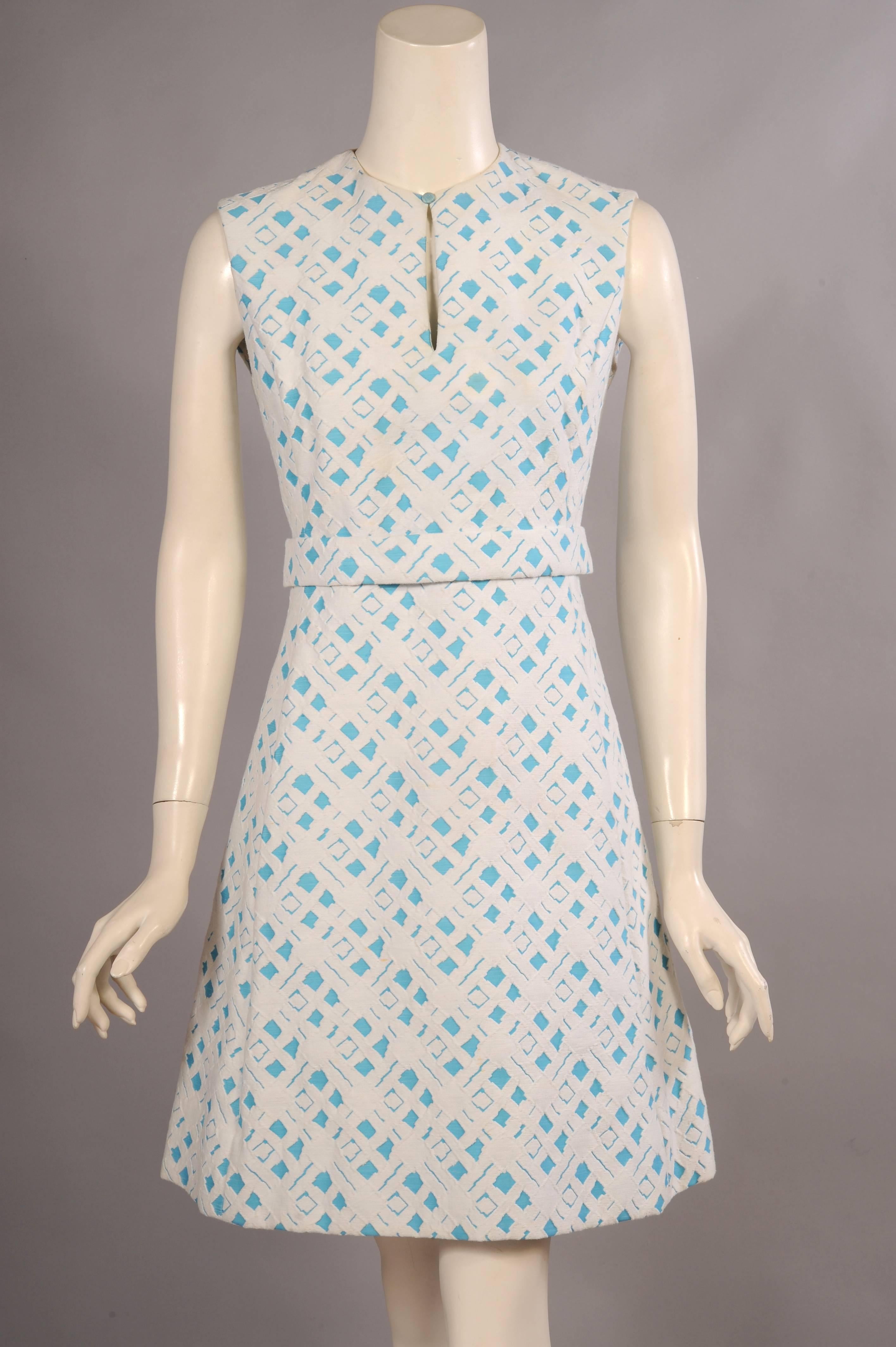 Crisp turquoise and white cotton matelassé is used for both pieces of this classic 1960's dress and coat ensemble from Ceil Chapman. The coat has a snap closure with five decorative jeweled buttons. There are two pockets concealed in the seams, and