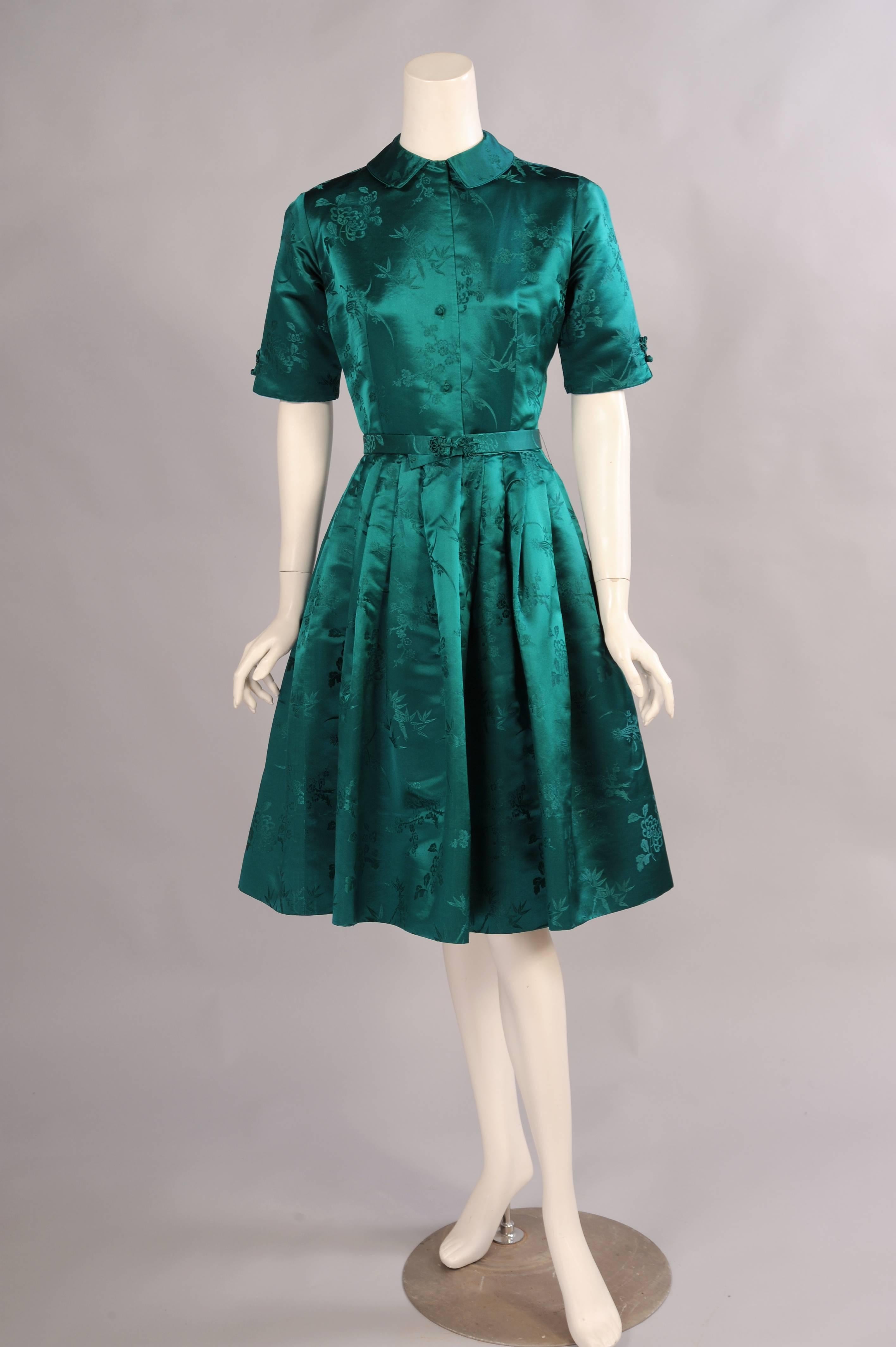 Ein reicher und eleganter chinesischer Seidensatin ist mit floralen Mustern gewebt und mit Seidenfröschen besetzt:: um ein auffälliges:: asiatisch inspiriertes Kleid zu schaffen. In der vorderen Mitte befinden sich Froschverschlüsse:: die sich auch