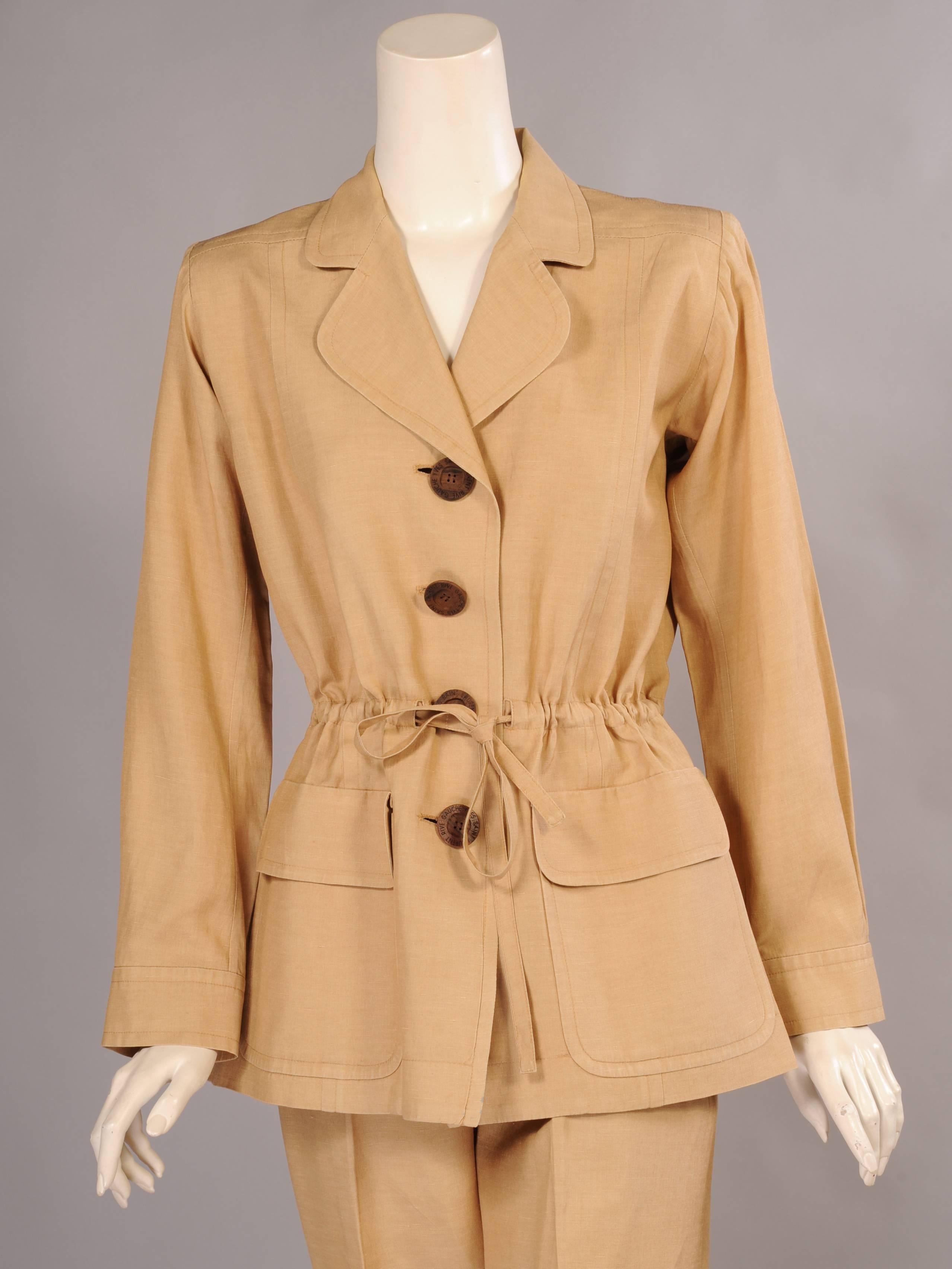 A perennial favorite from YSL, the safari suit has been designed in a number of variations. This version is silk, and the jacket has a tailored look. There is a notched collar, brown wooden logo buttons, a drawstring waist and two flap pockets. The