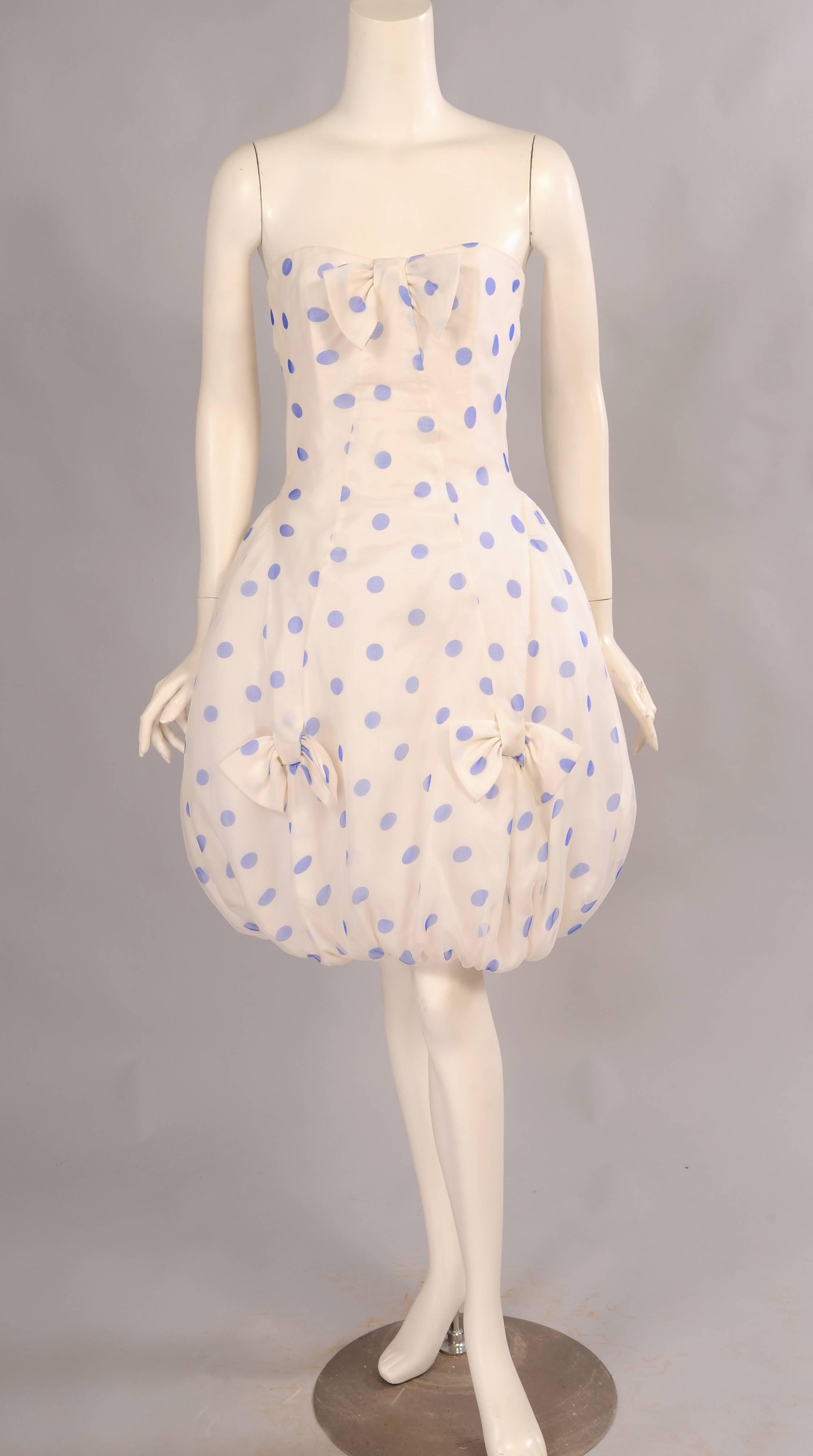 Quite a departure for Hanae Mori this dress has great big blue polka dots on a white organza background. The strapless dress has a boned bodice and a bow at the front. The pouf skirt has two more bows on each side and one at the center back