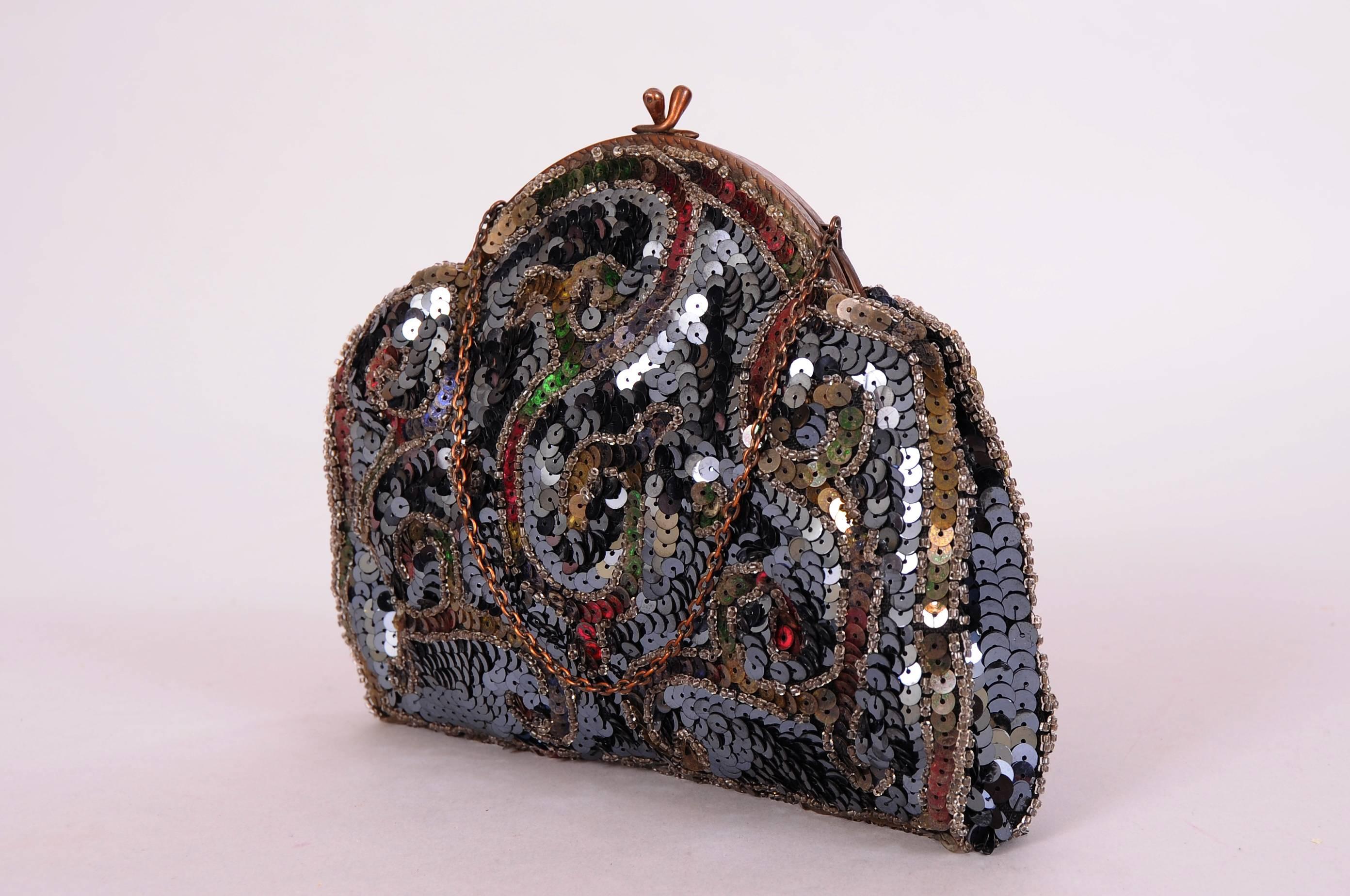 A gold toned frame with a kiss lock closure sits atop this glistening bag. It is covered with multi color sequins and clear caviar beads in a swirling design. The bag is lined in black silk and marked Made in France. It is in excellent