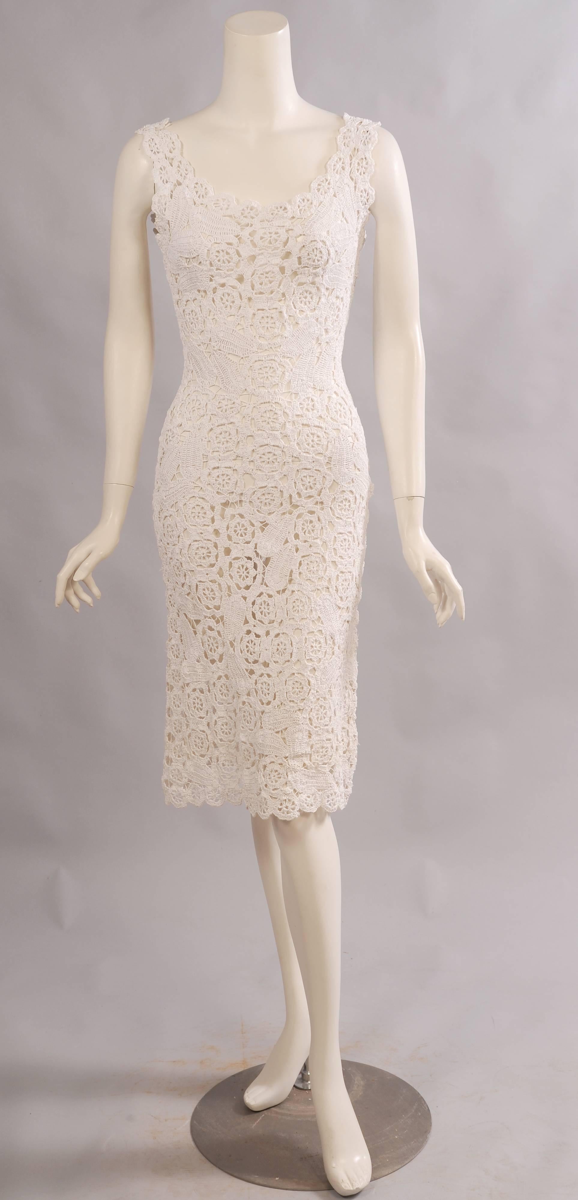 Beautifully hand made from white raffia this 1960's sleeveless sheath has a low neckline edged with white raffia roundels. The dress is fitted through the torso with a left side metal zipper. The hem is scalloped with matching roundels. This lovely