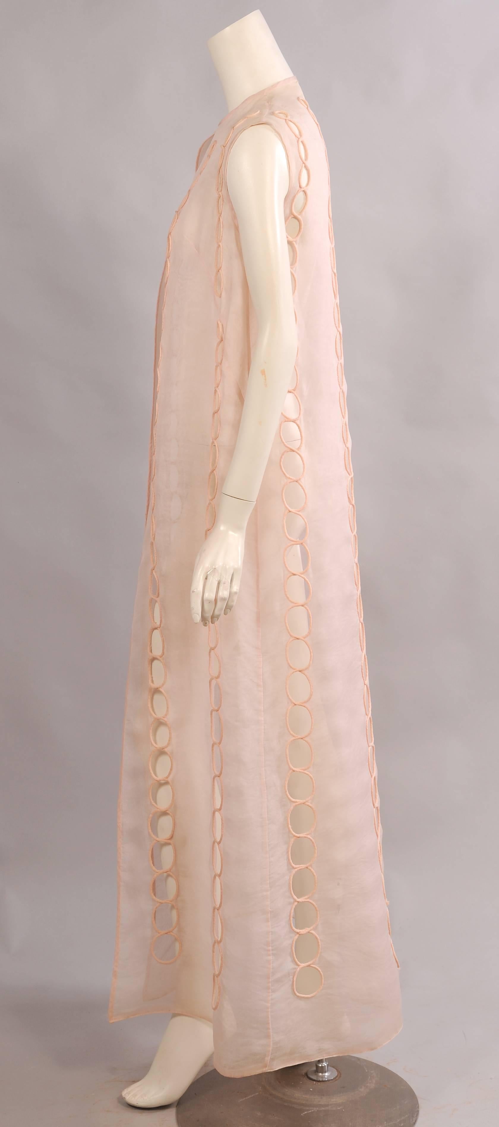 Sheer pale pink silk organza is used for this long vest or sleeveless summer coat. Vertical rows of graduated open circles are edged with matching pink piping. All of the edges are bound with pink organza and the hem has horsehair binding for added